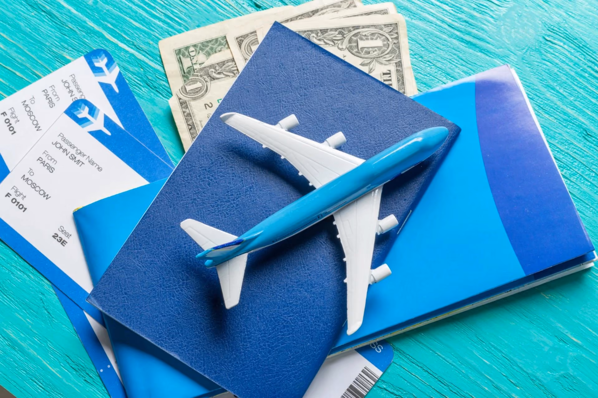 Flight tickets, passport, and toy plane with cash — entry level flight cost for New Zealand vs Switzerland