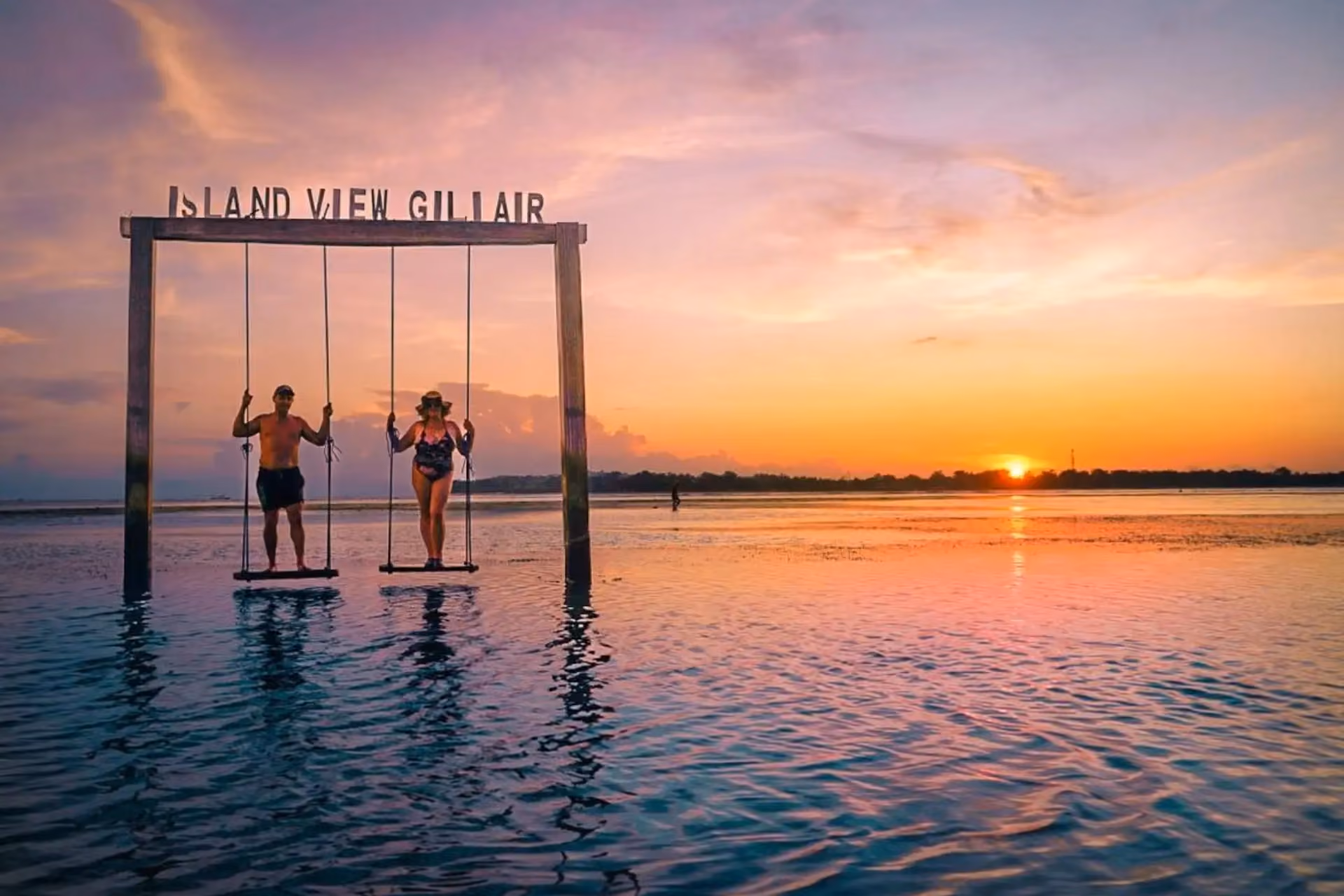 Two people on swings at Island View Gillair Bali sunset