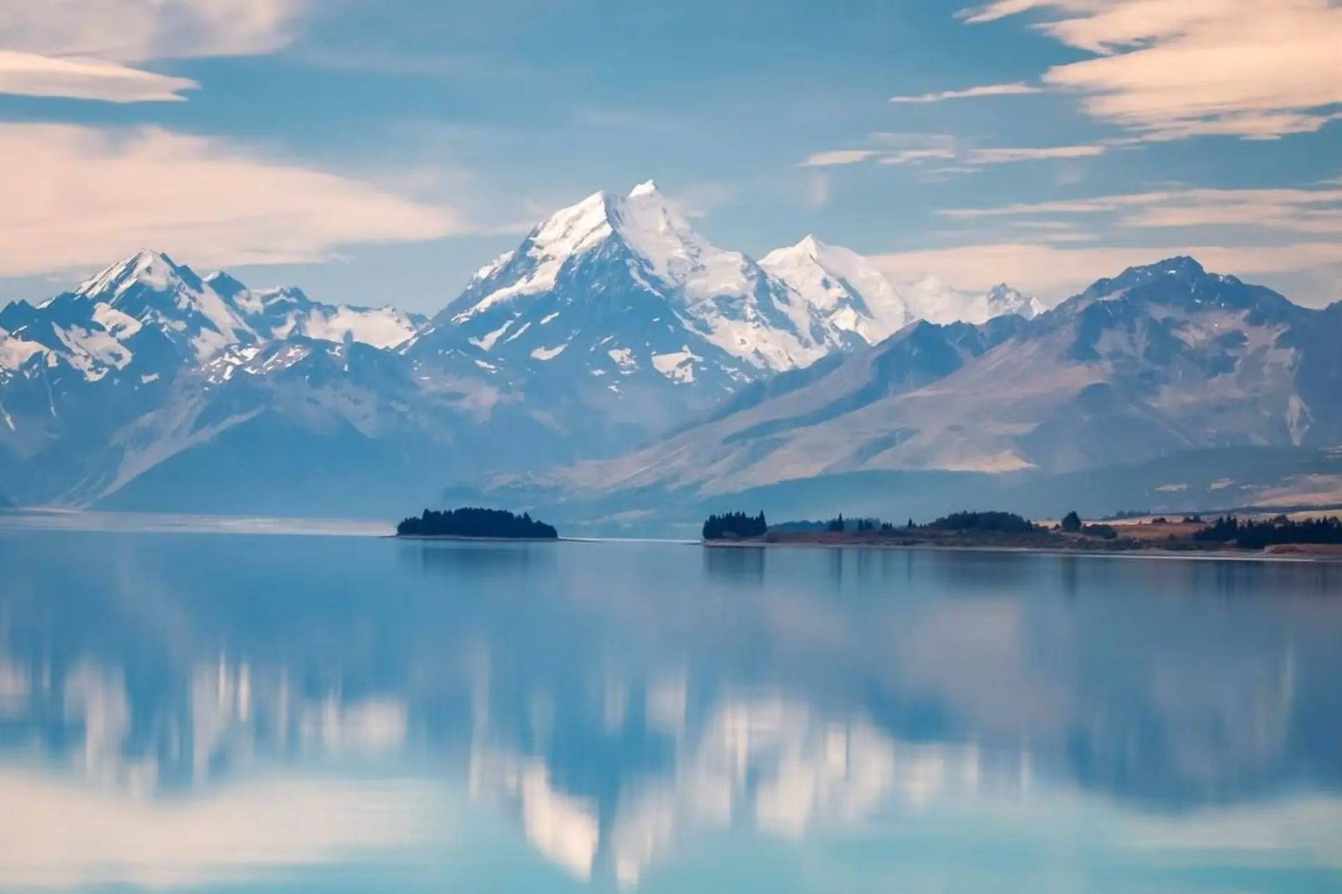Snow-covered Mount Cook reflected in calm lake water, New Zealand
