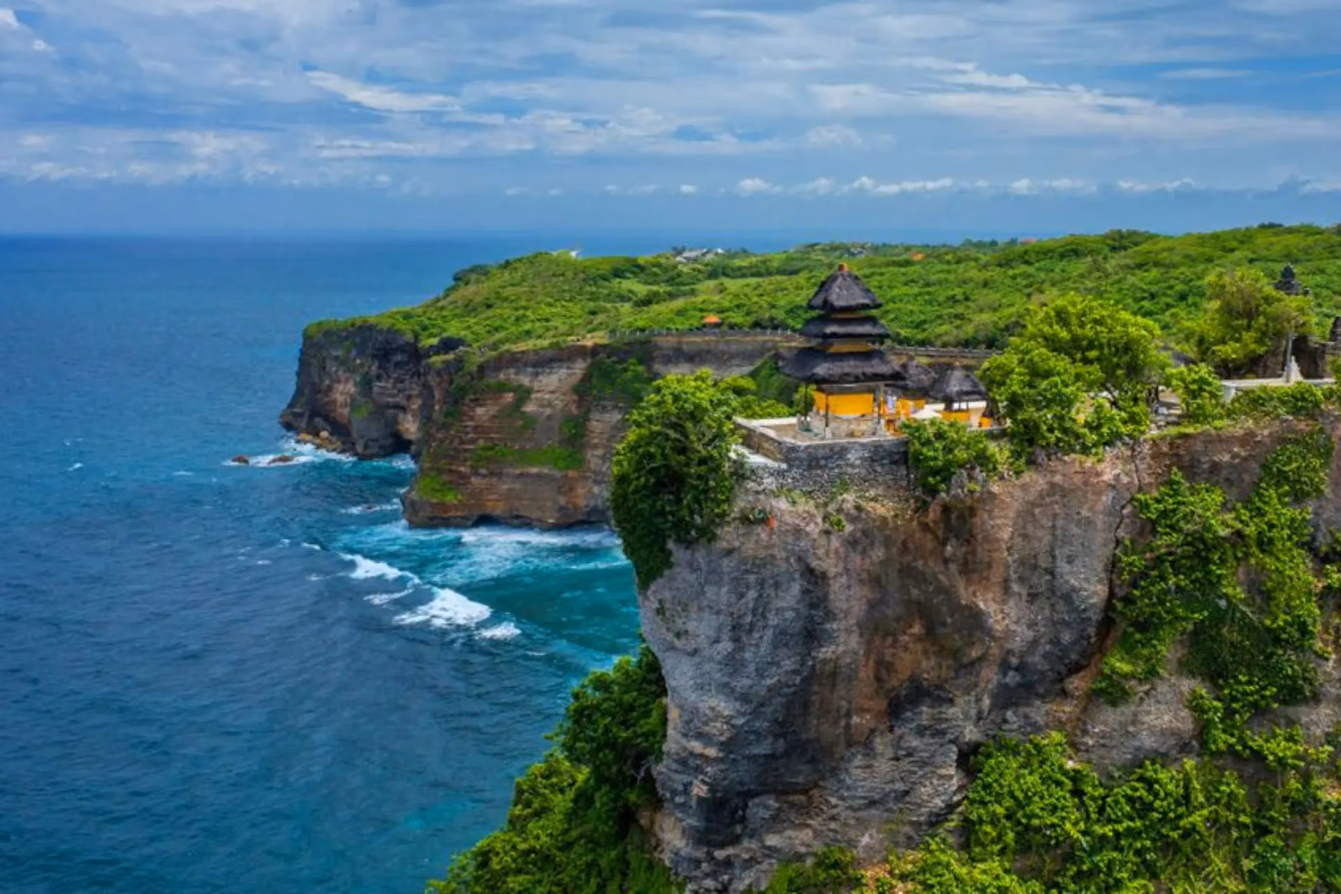 Temple with yellow roof on cliff edge at Uluwatu Bali