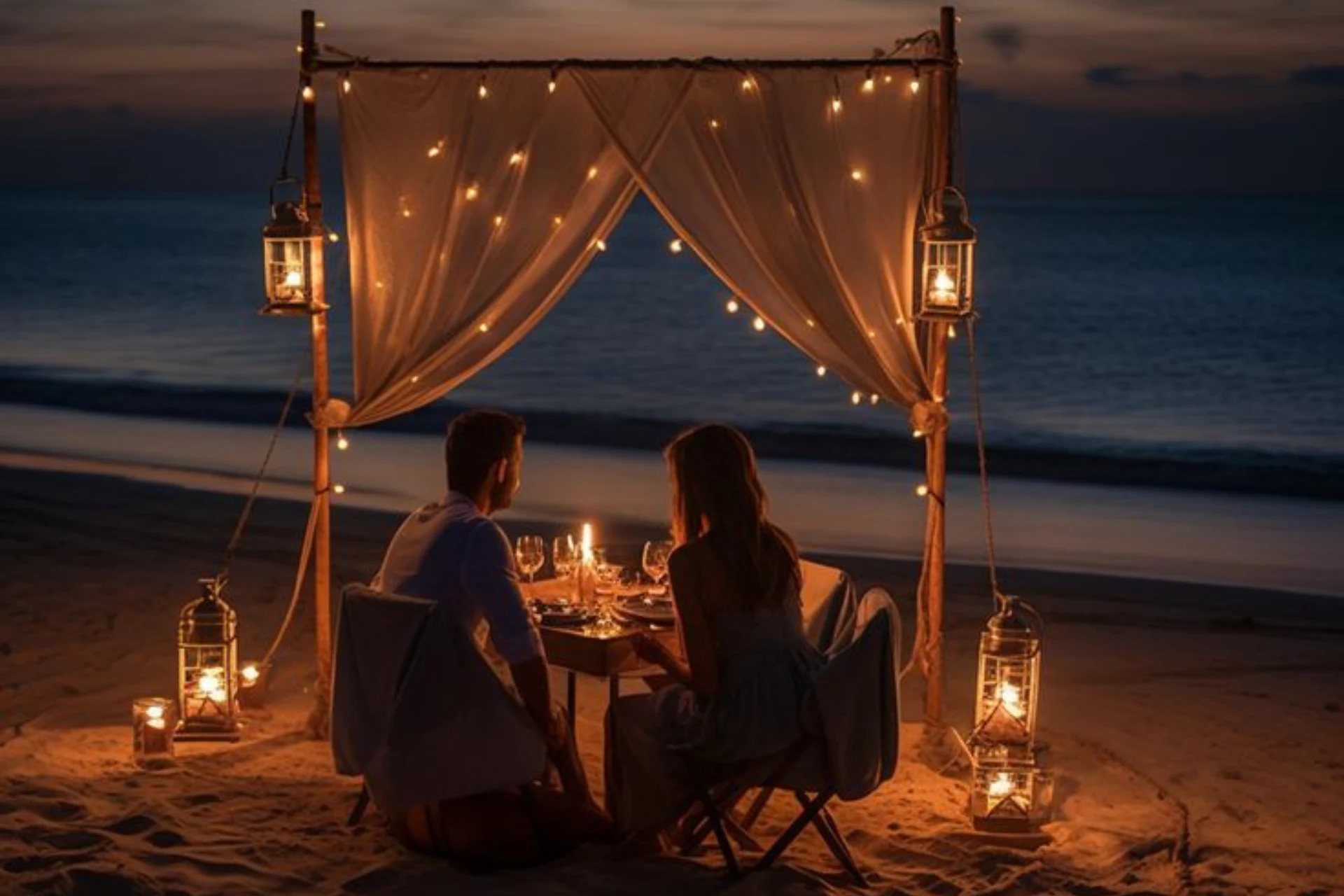Couple dining under lit curtains at Ombak beach sunset