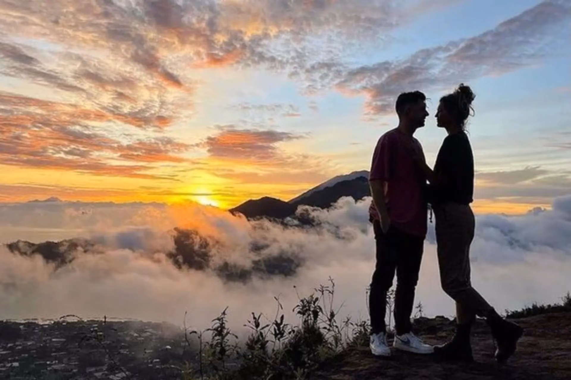 Couple watching sunrise over clouds at Mt. Batur