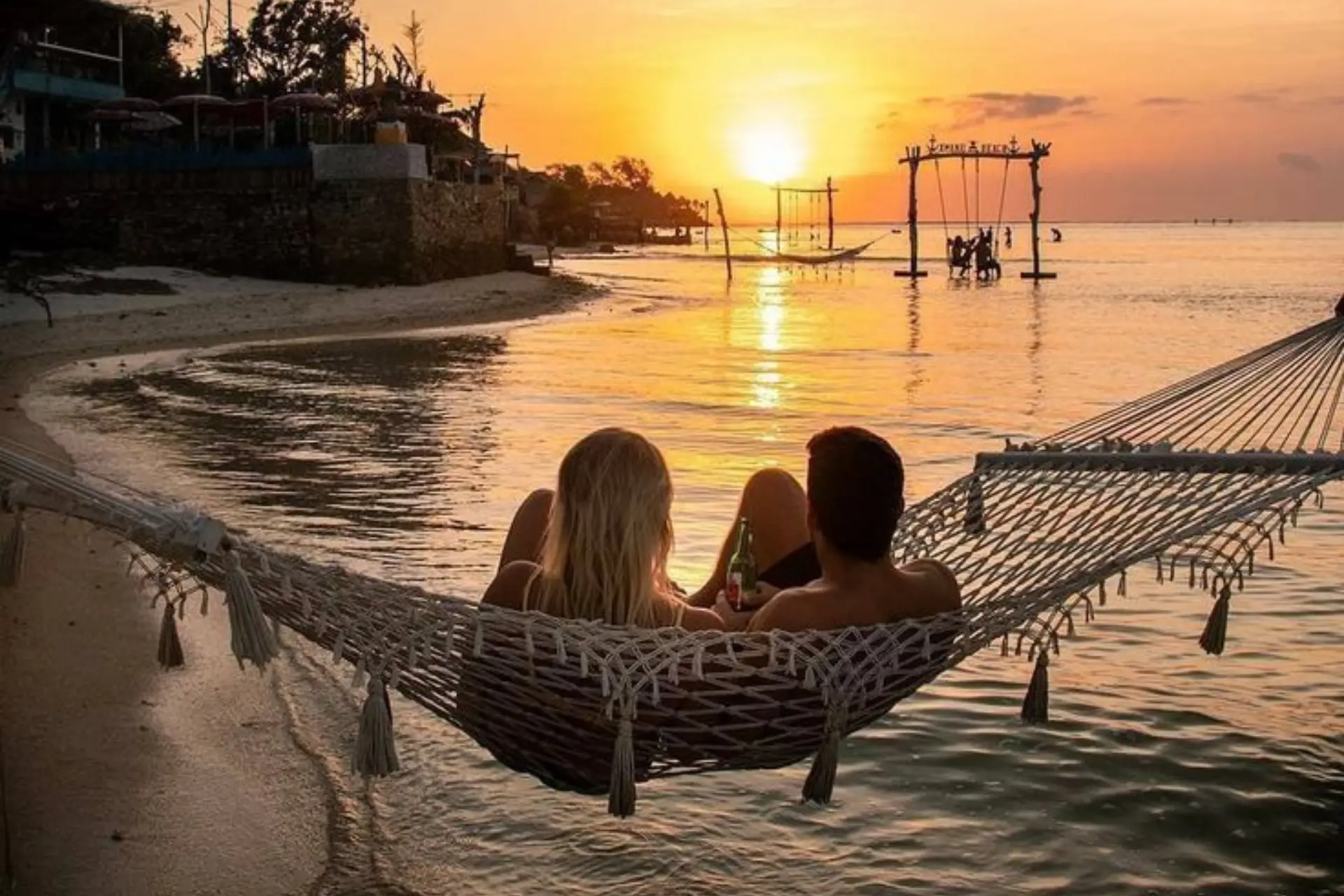 People in hammock at sunset beach Bali