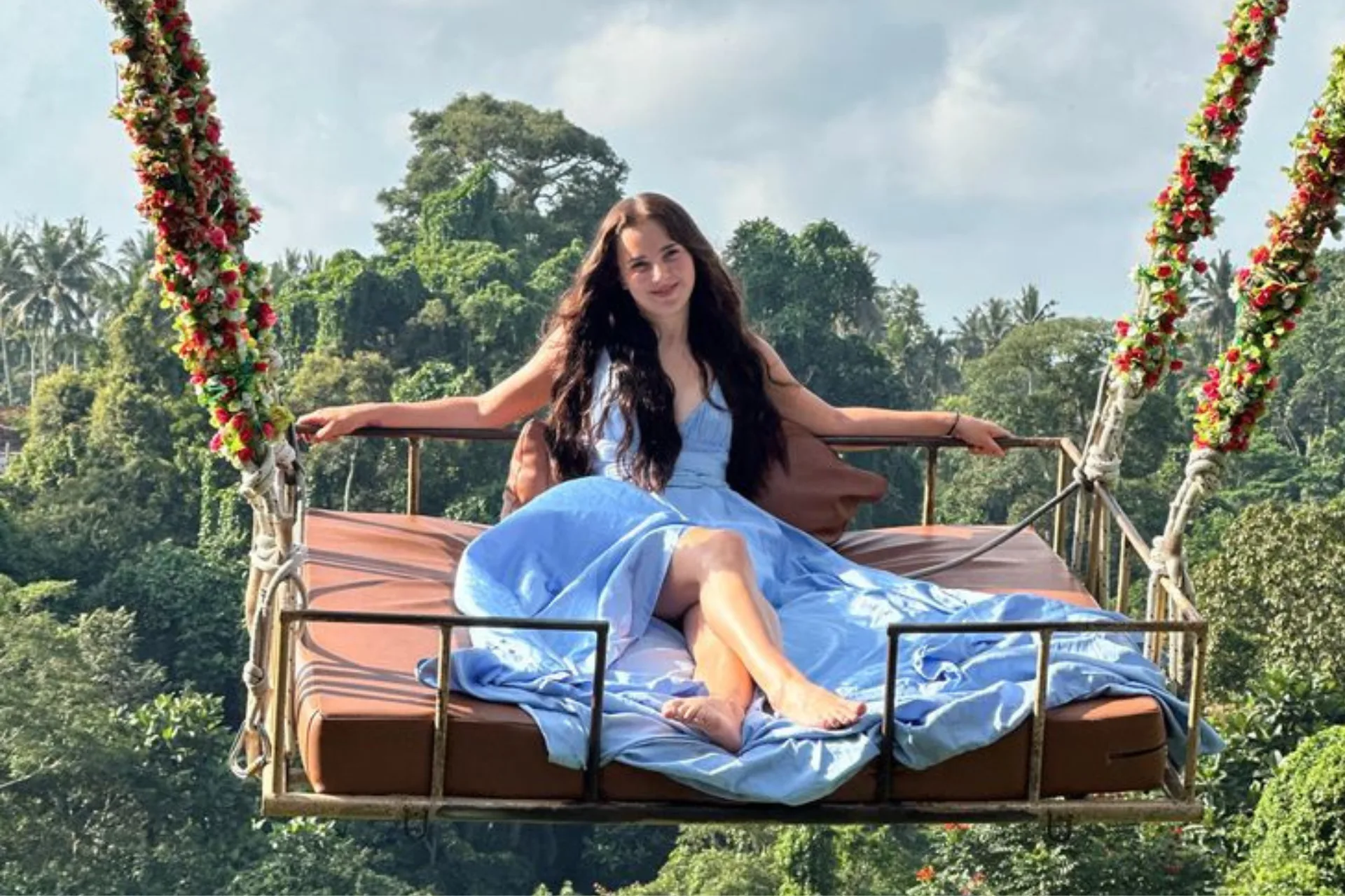 Woman on hanging bed swing over jungle forest