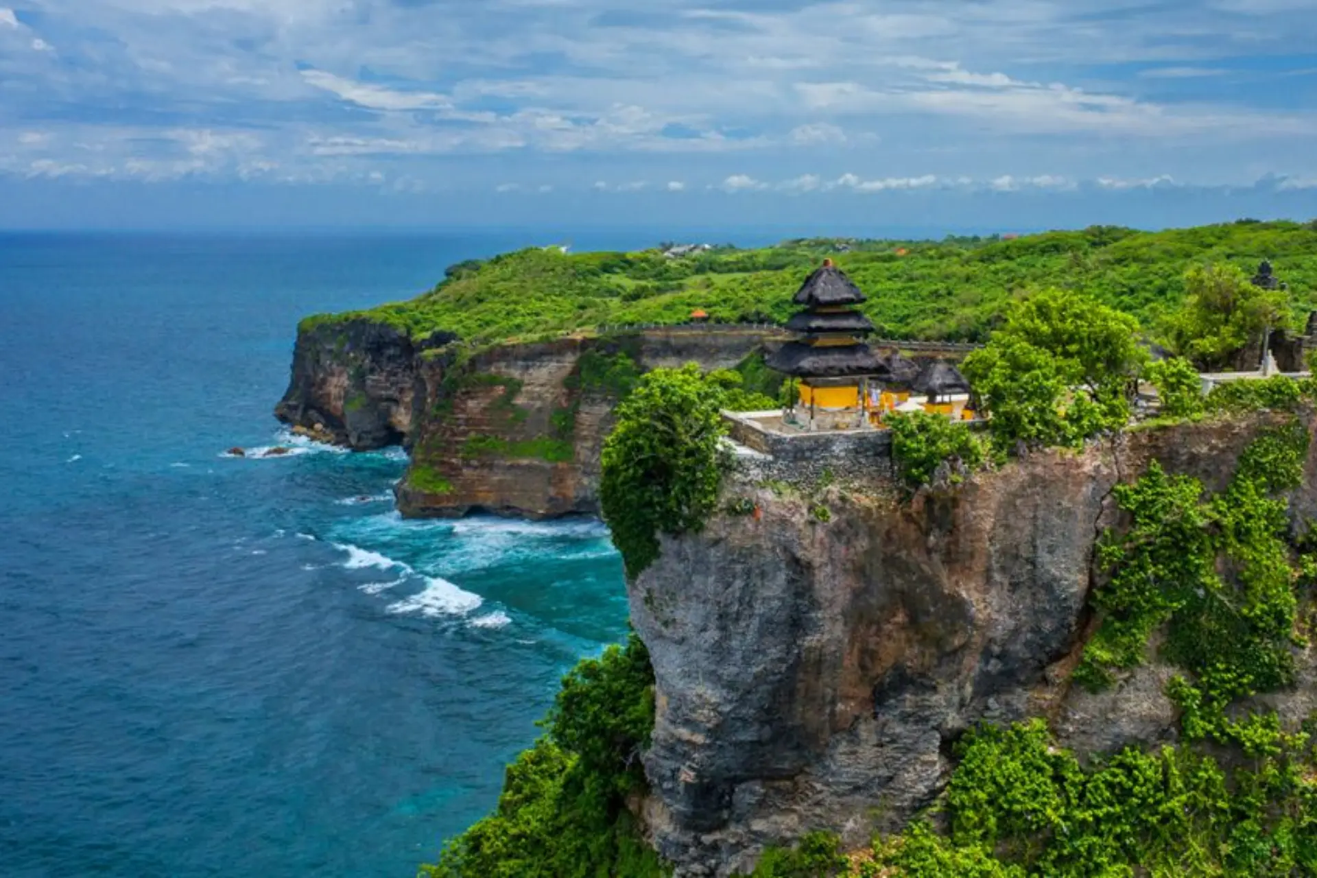 Temple with yellow roof on cliff edge at Uluwatu Bali