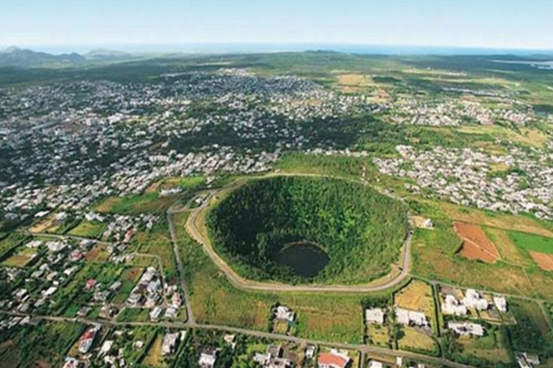 Trou Aux Cerfs volcanic crater surrounded by green forest and town