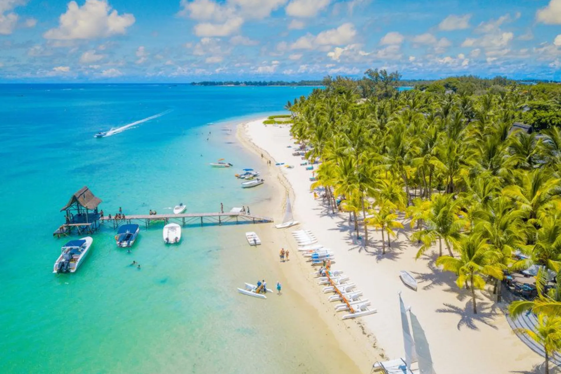 Mauritius beach with palm trees and boats in clear water
