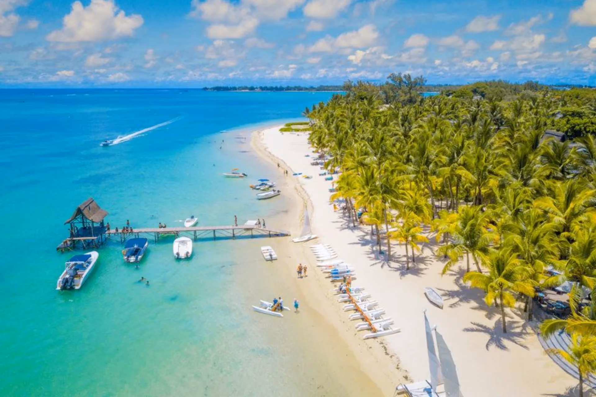 Mauritius beach with palm trees and boats in clear water