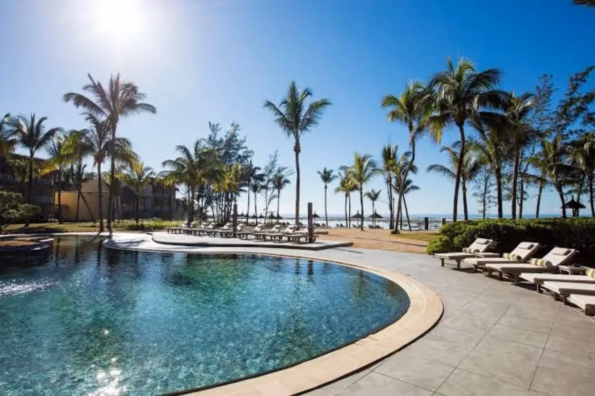 Resort pool with palm trees overlooking beach in Mauritius
