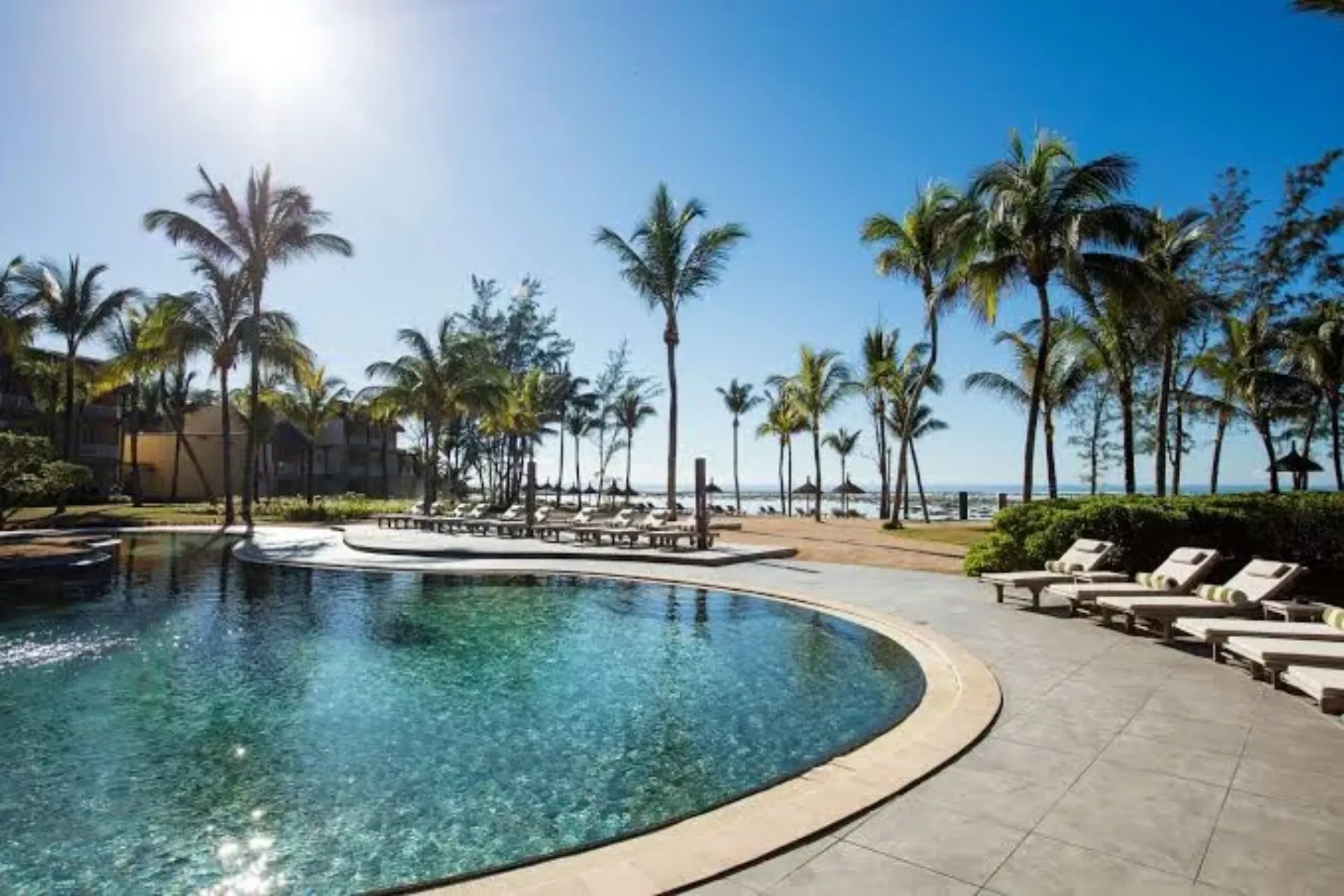 Resort pool with palm trees overlooking beach in Mauritius