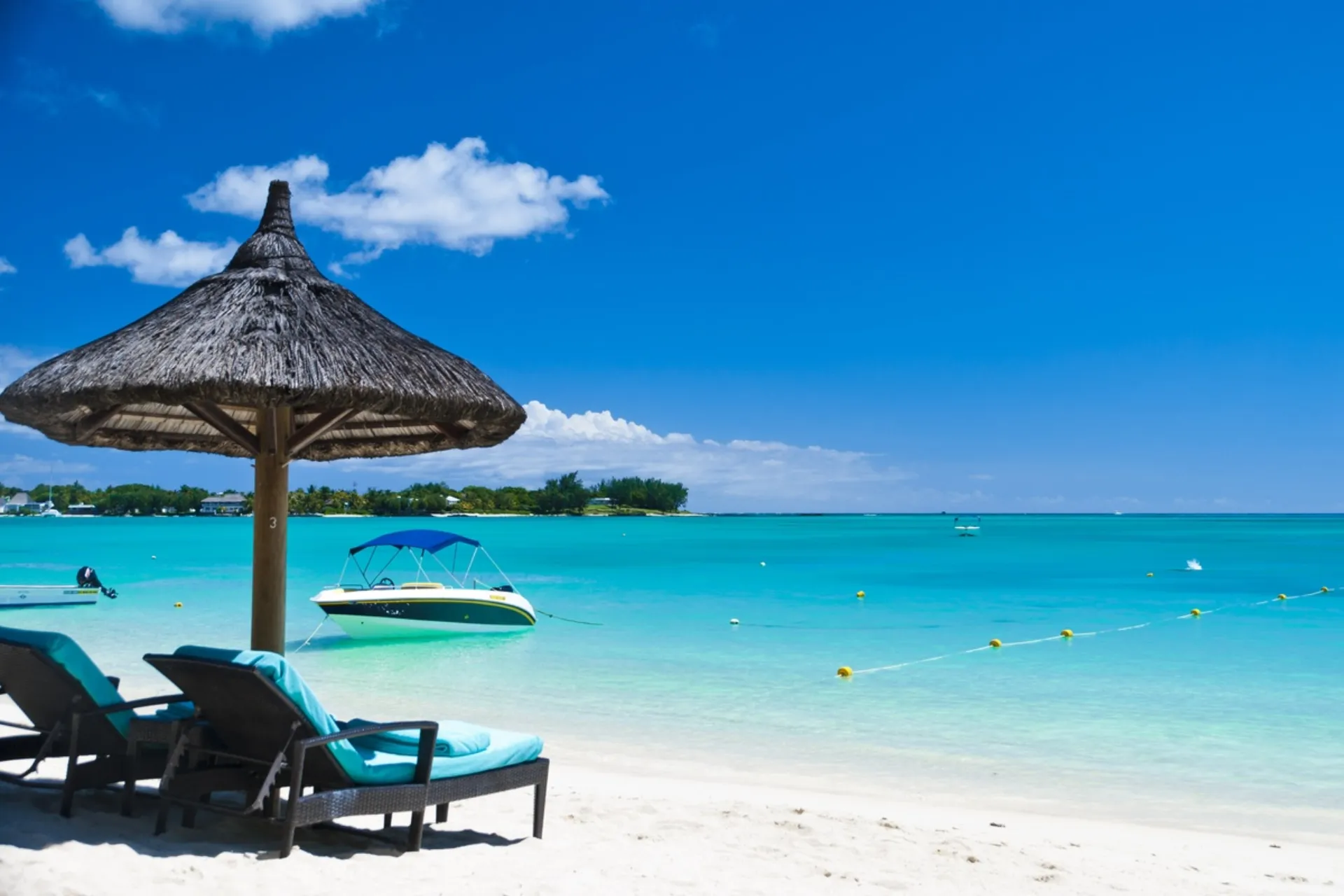 Thatched umbrella and lounge chairs on Mauritius beach