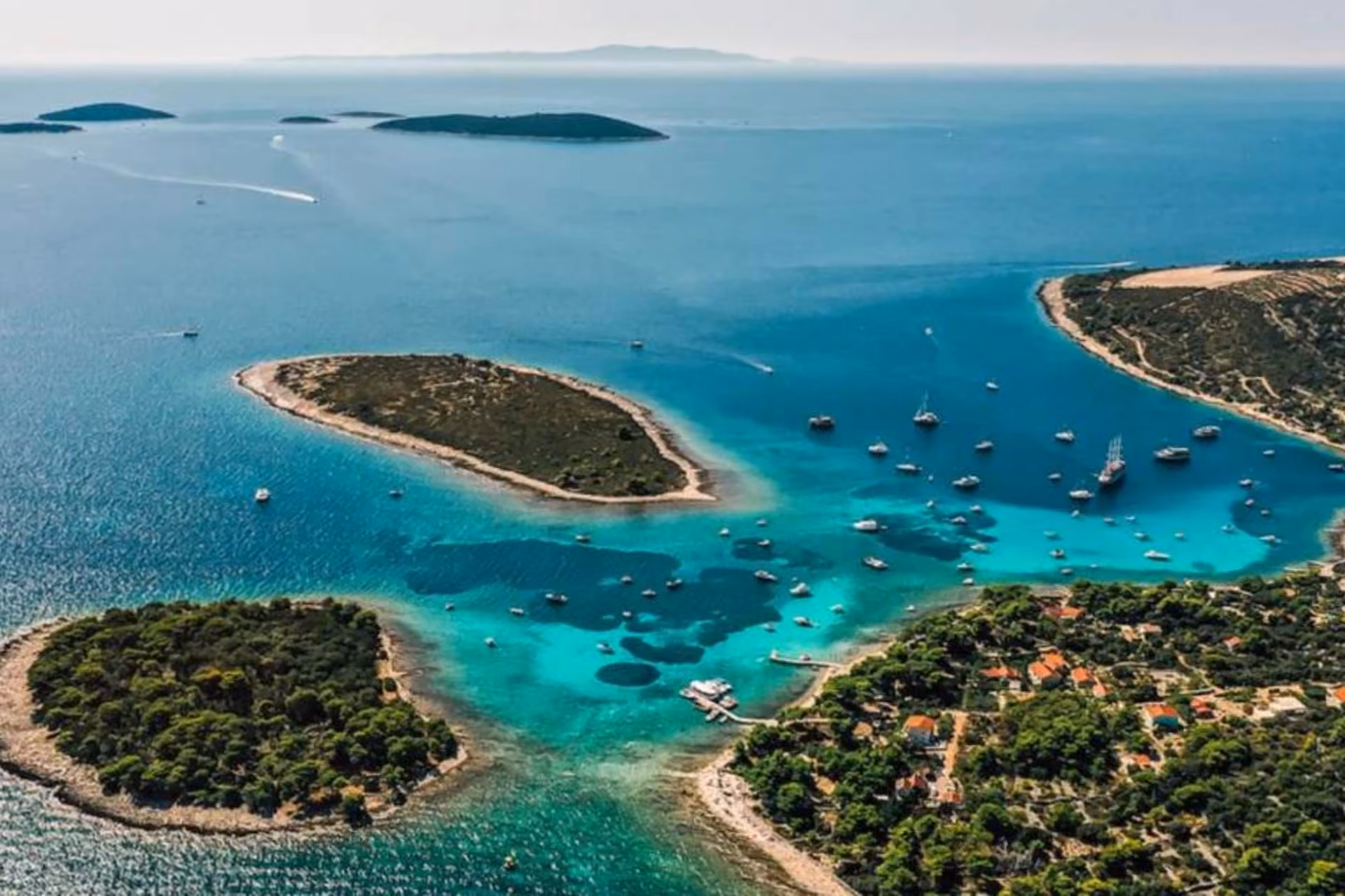 Three green islands with boats in clear blue water