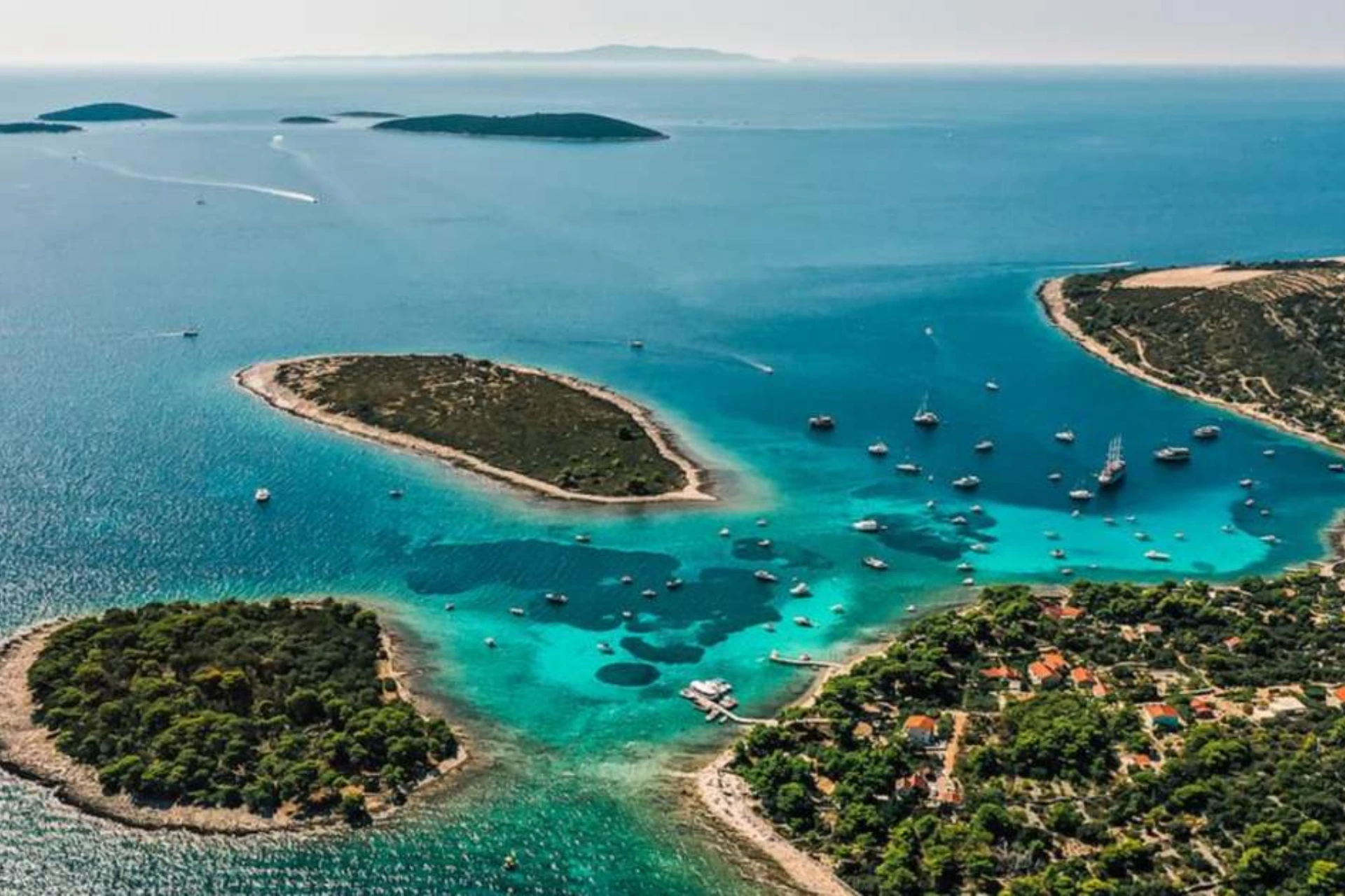 Three green islands with boats in clear blue water