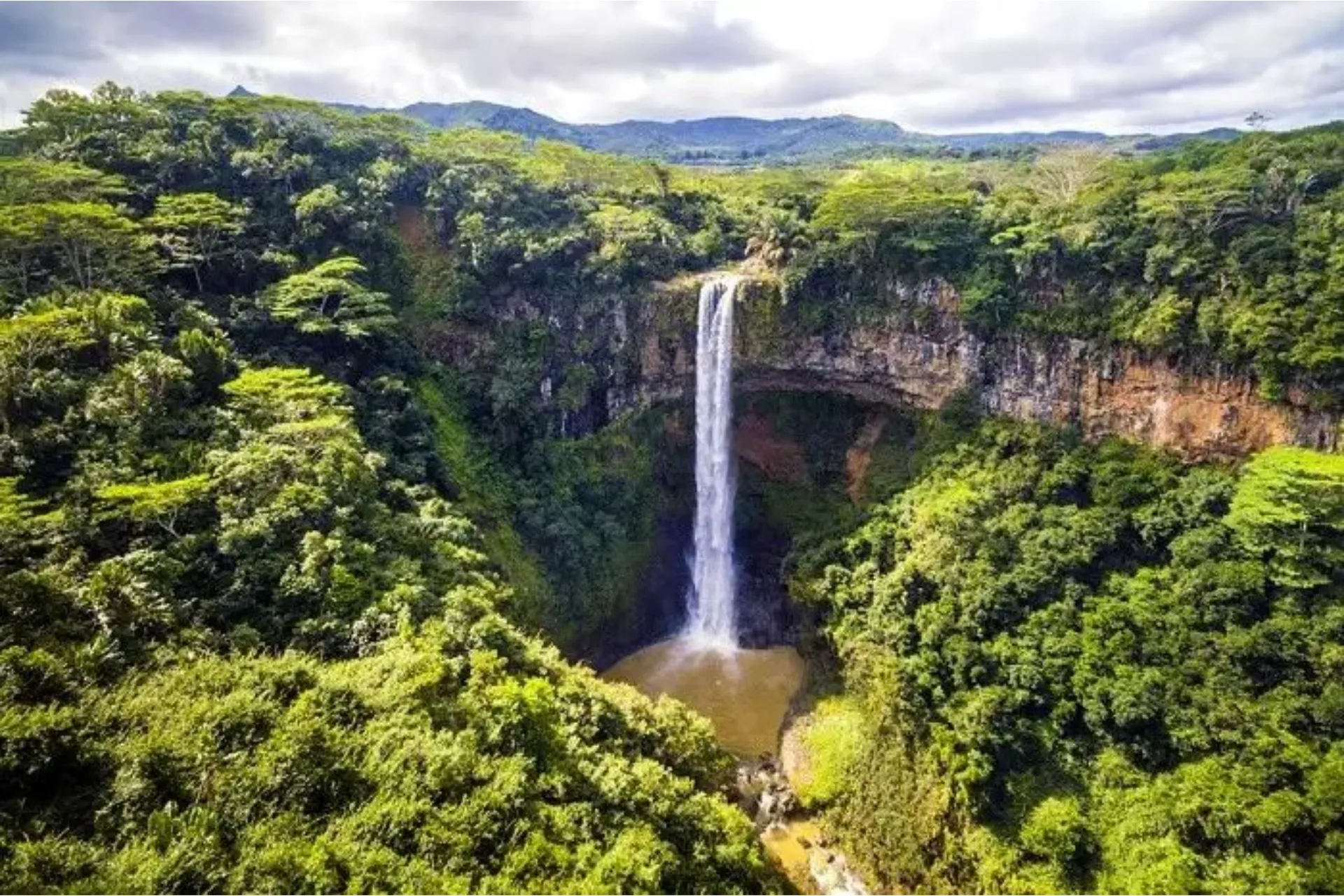 Waterfall flowing into pool surrounded by green forest, Mauritius