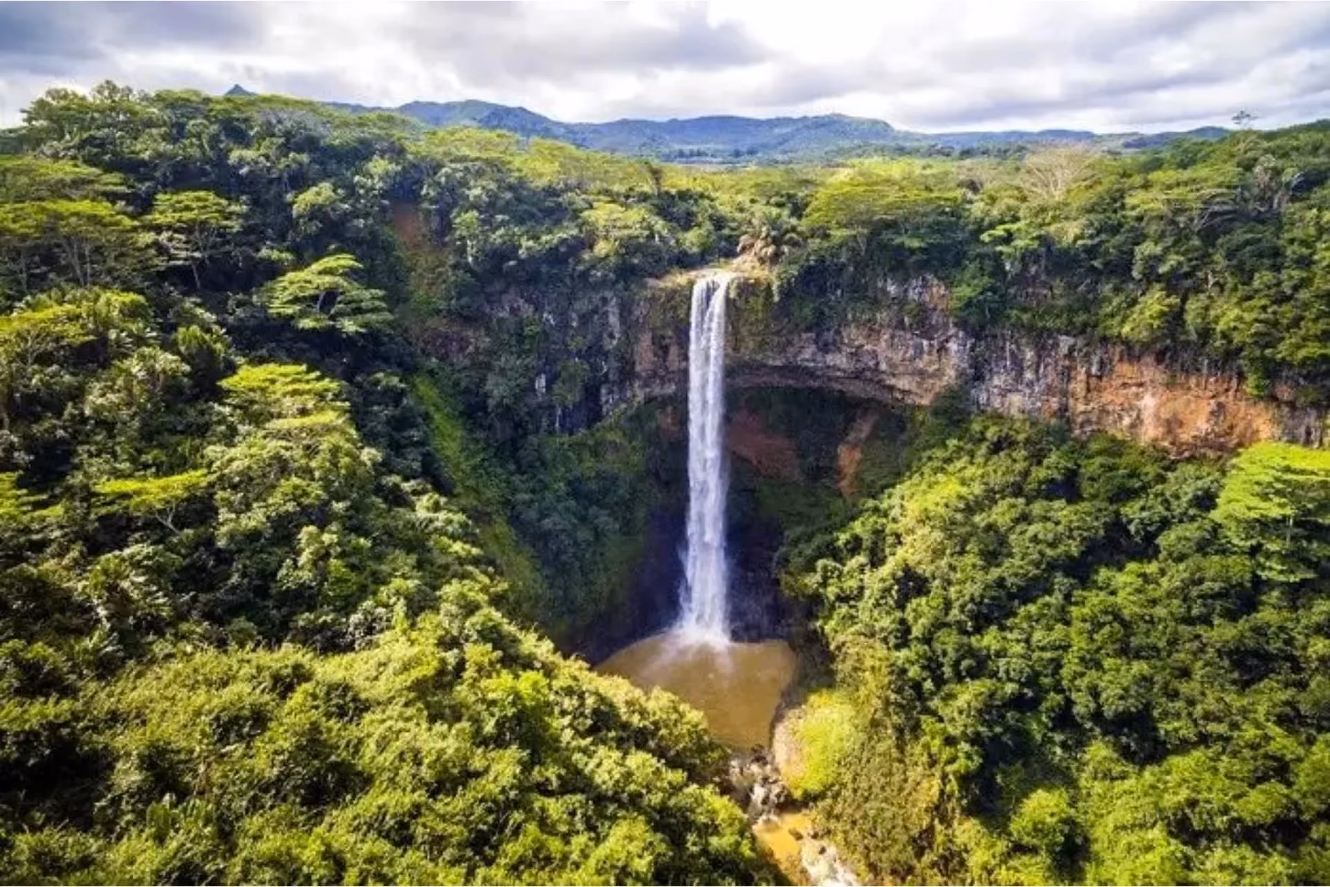 Waterfall flowing into pool surrounded by green forest, Mauritius
