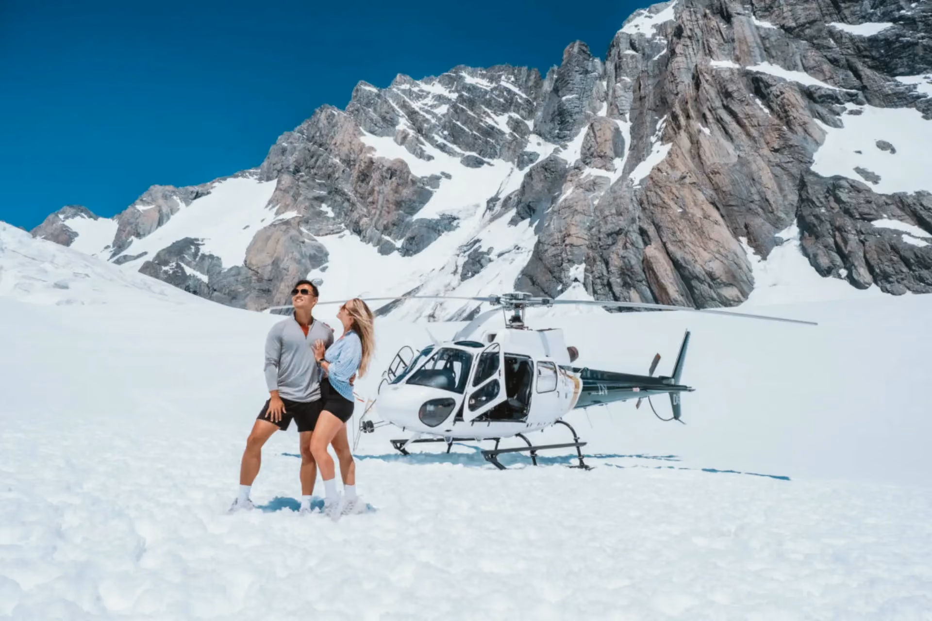 Couple standing on snow with helicopter at Mount Cook New Zealand