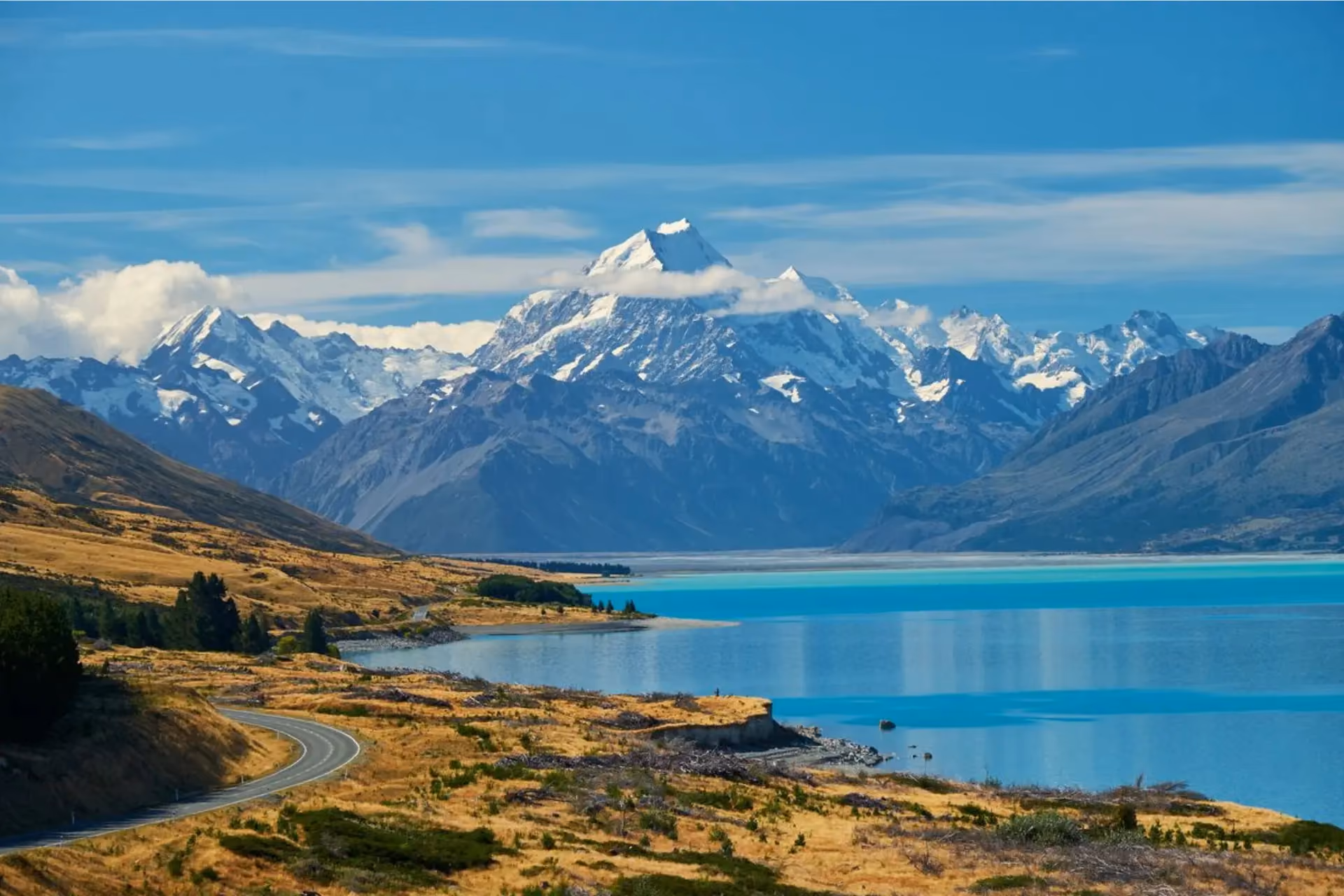 Snow-capped Mount Cook with blue lake and winding road New Zealand
