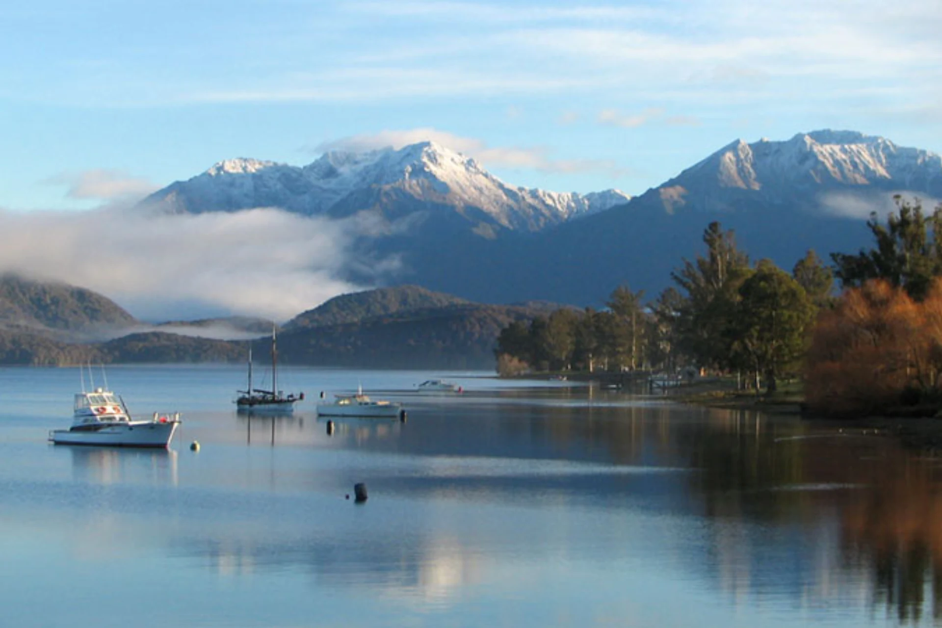 Boats on calm lake with snow mountains, Te Anau New Zealand