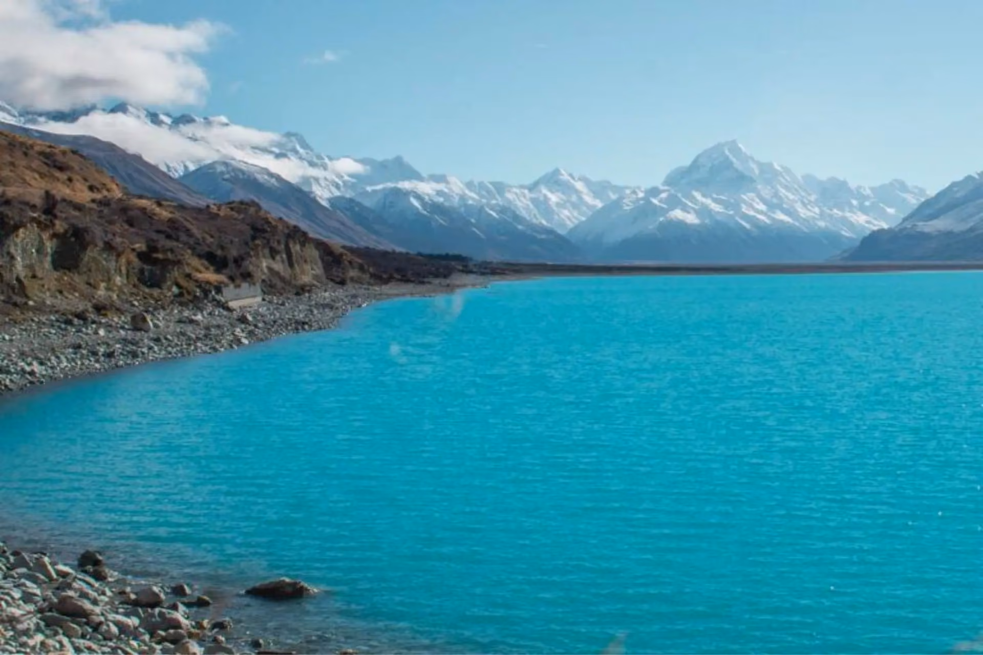 Bright blue water at Lake Tekapo with snow mountains behind