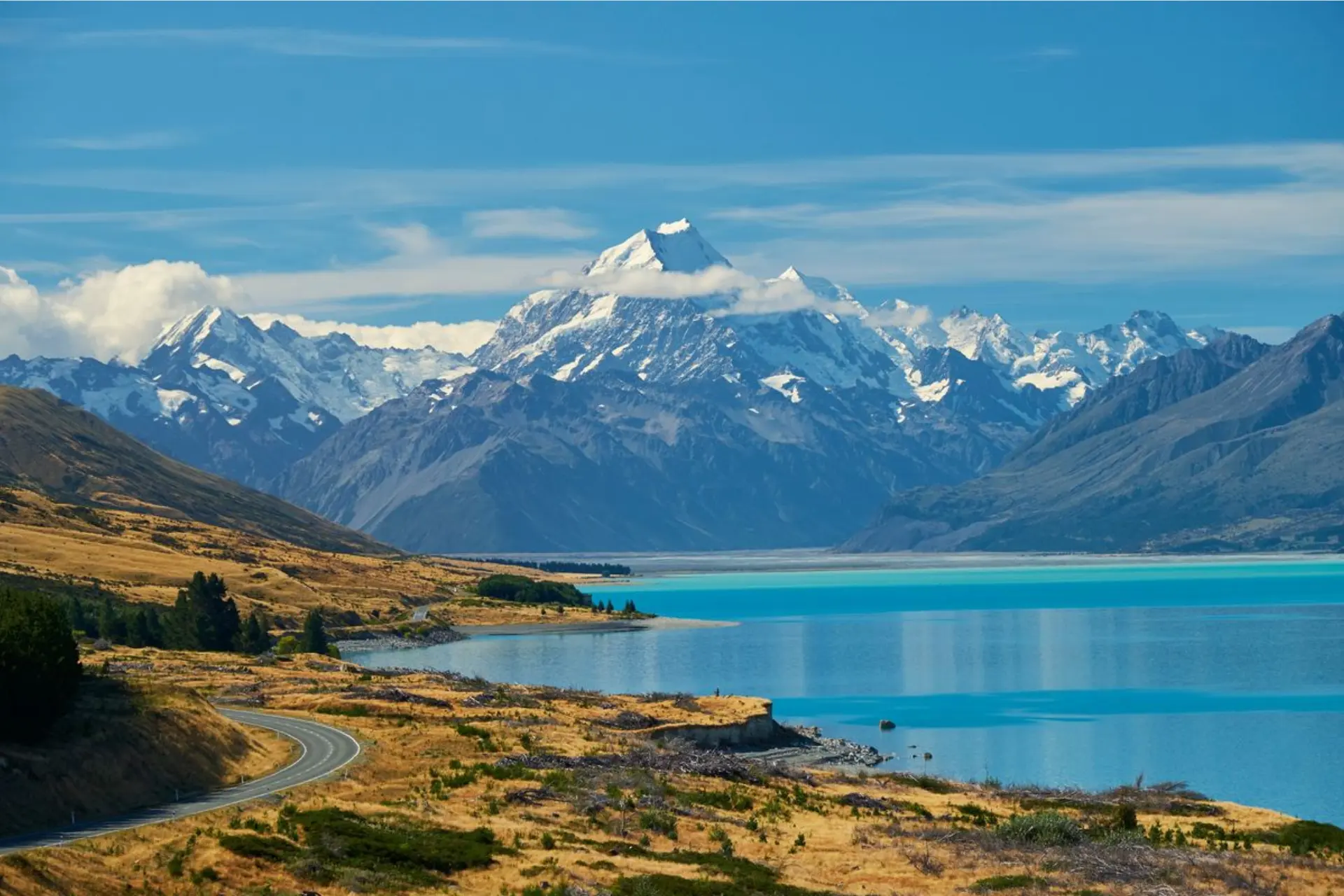Snow-capped Mount Cook with blue lake and winding road New Zealand