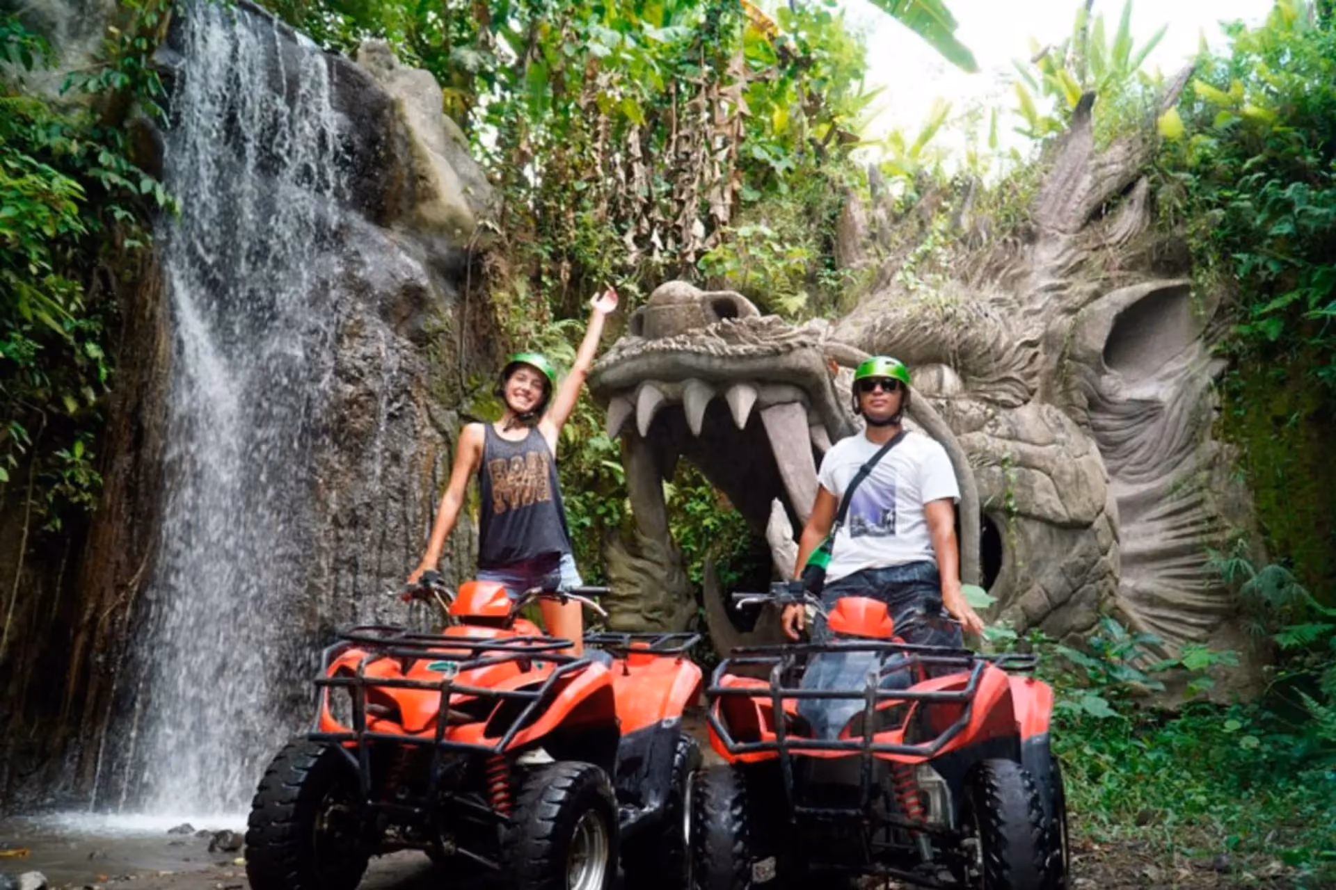 Two people on red ATVs near stone dragon statue, Bali