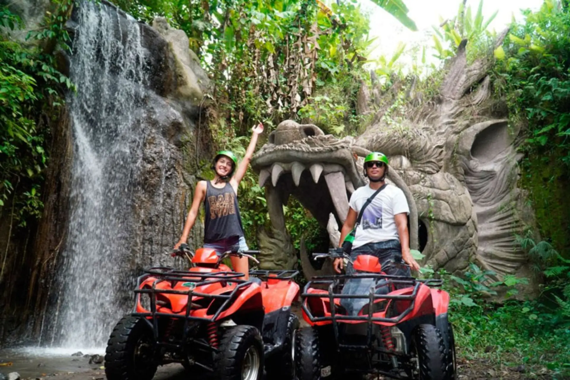 Two people on red ATVs near stone dragon statue, Bali