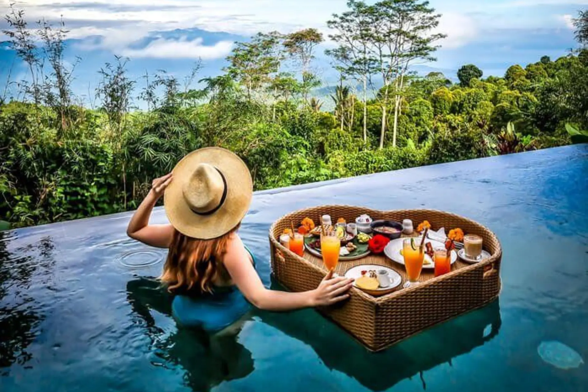 Woman in pool eating breakfast on floating basket in Bali