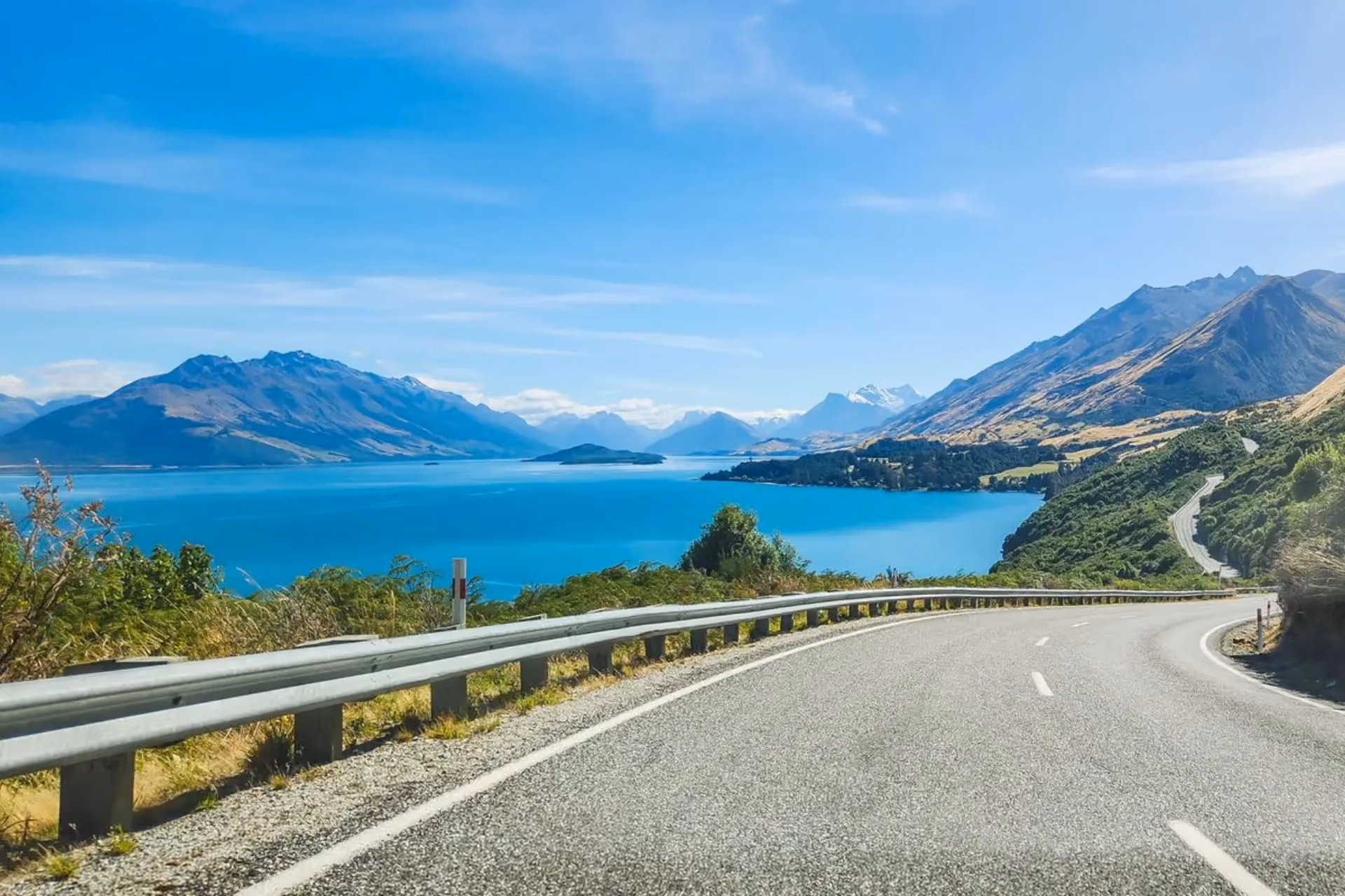 Road curving toward blue lake and mountains in Akaroa