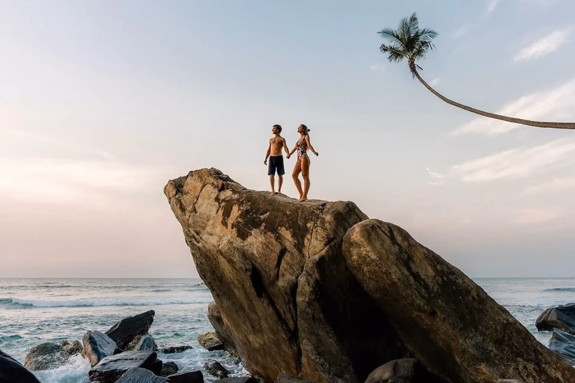 Two people standing on large rock at Ahangama Beach Sri Lanka