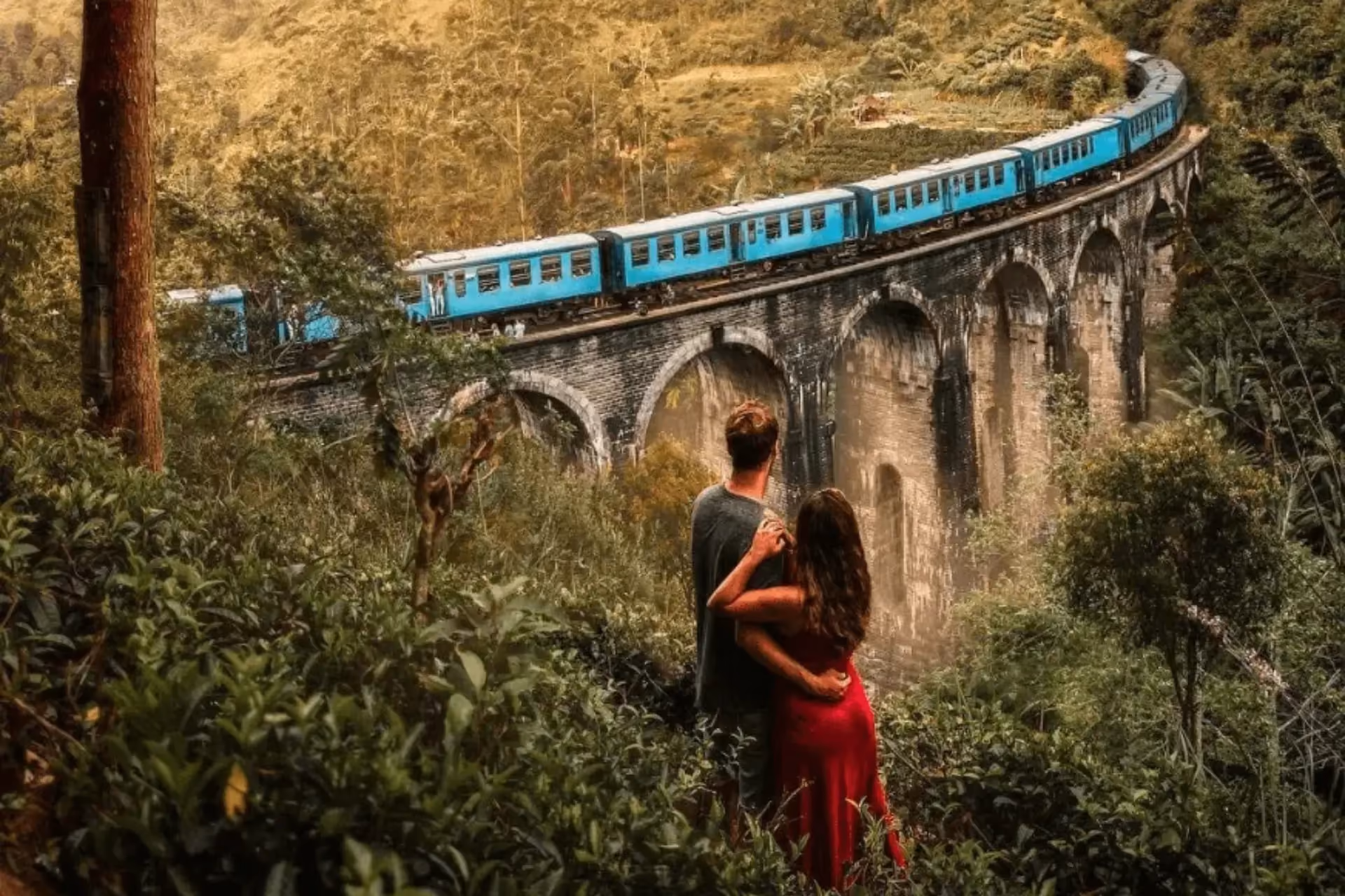 Couple watching blue train cross Nine Arch Bridge Sri Lanka