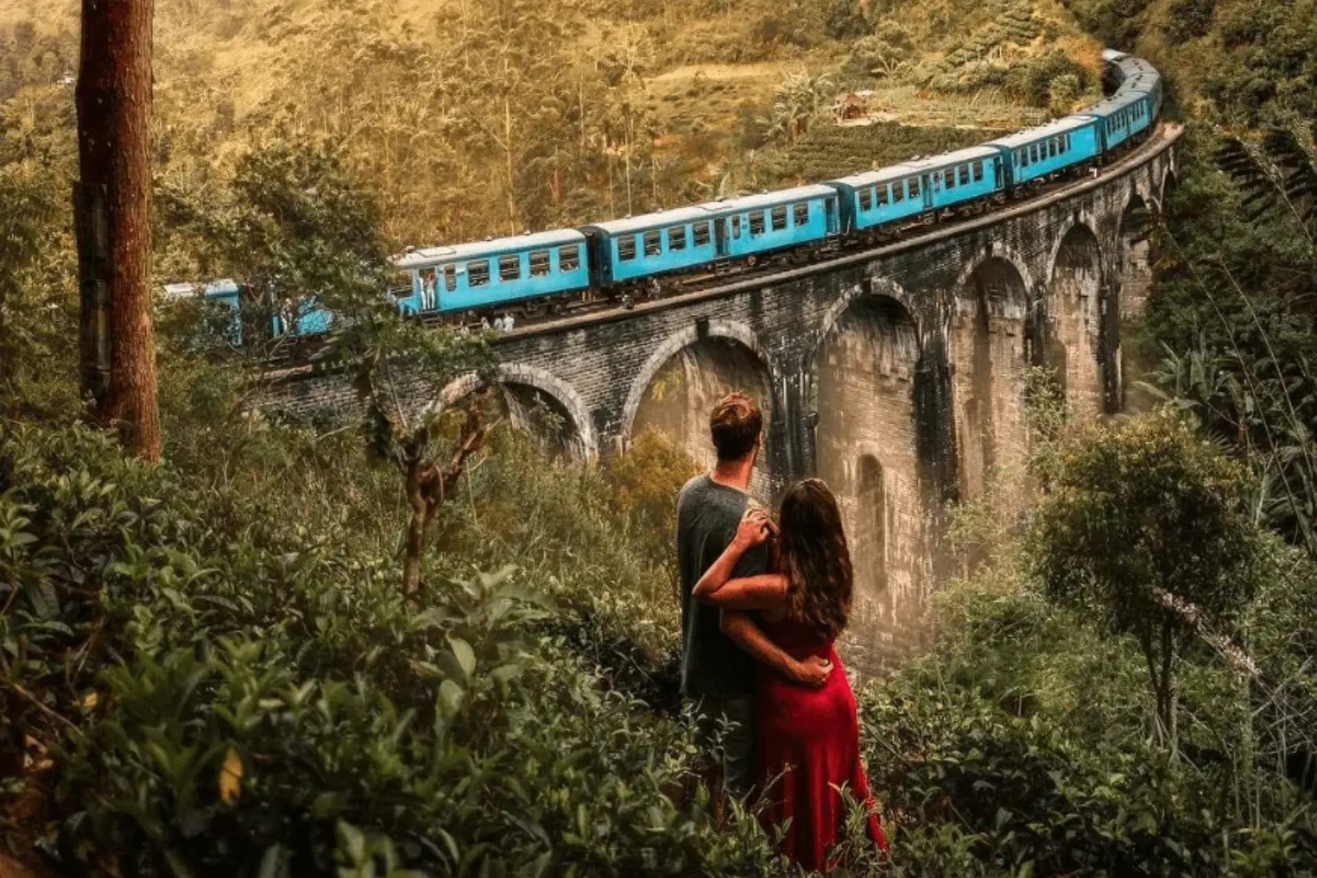 Couple watching blue train cross Nine Arch Bridge Sri Lanka