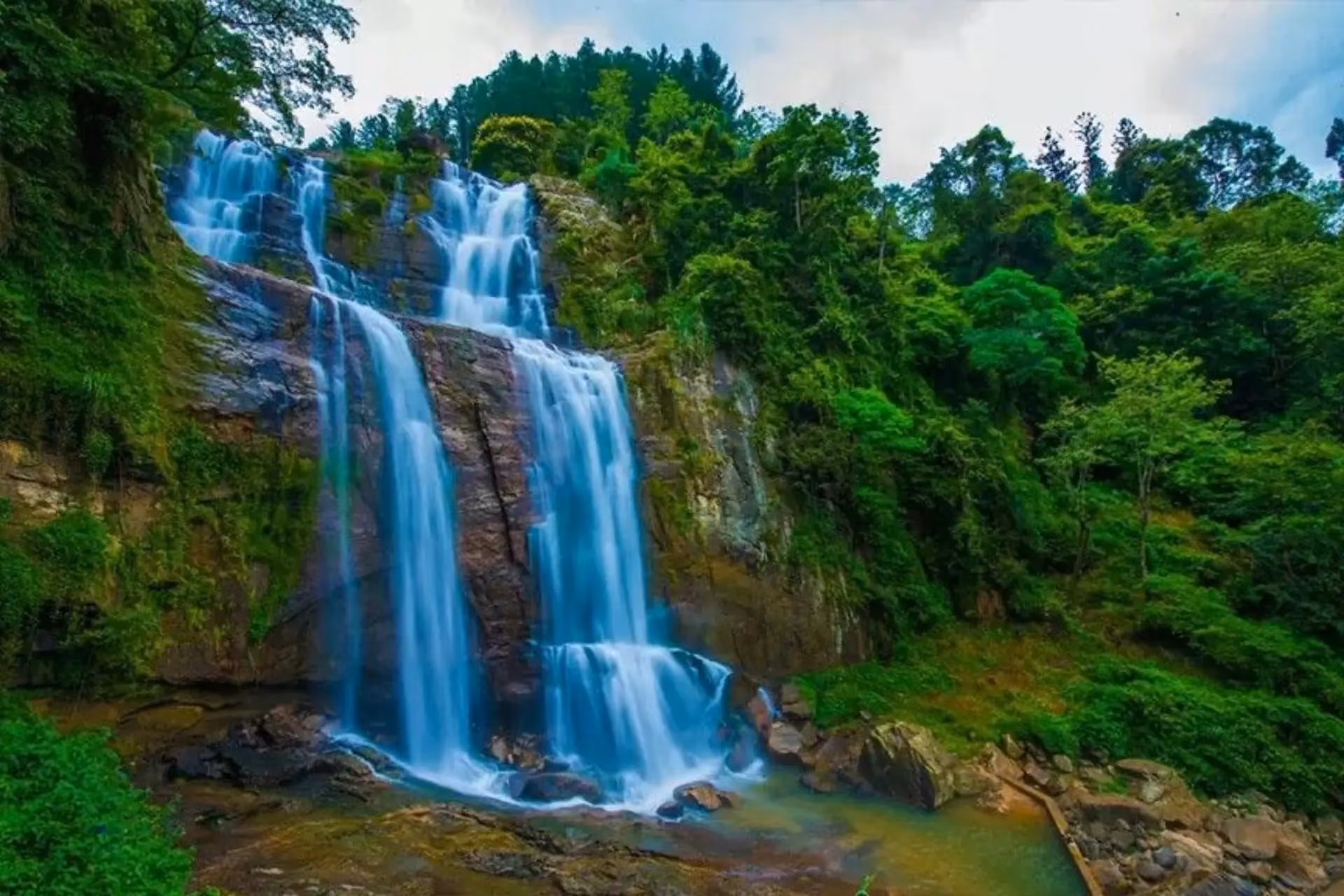Ramboda Falls cascading down rocky cliff surrounded by green forest