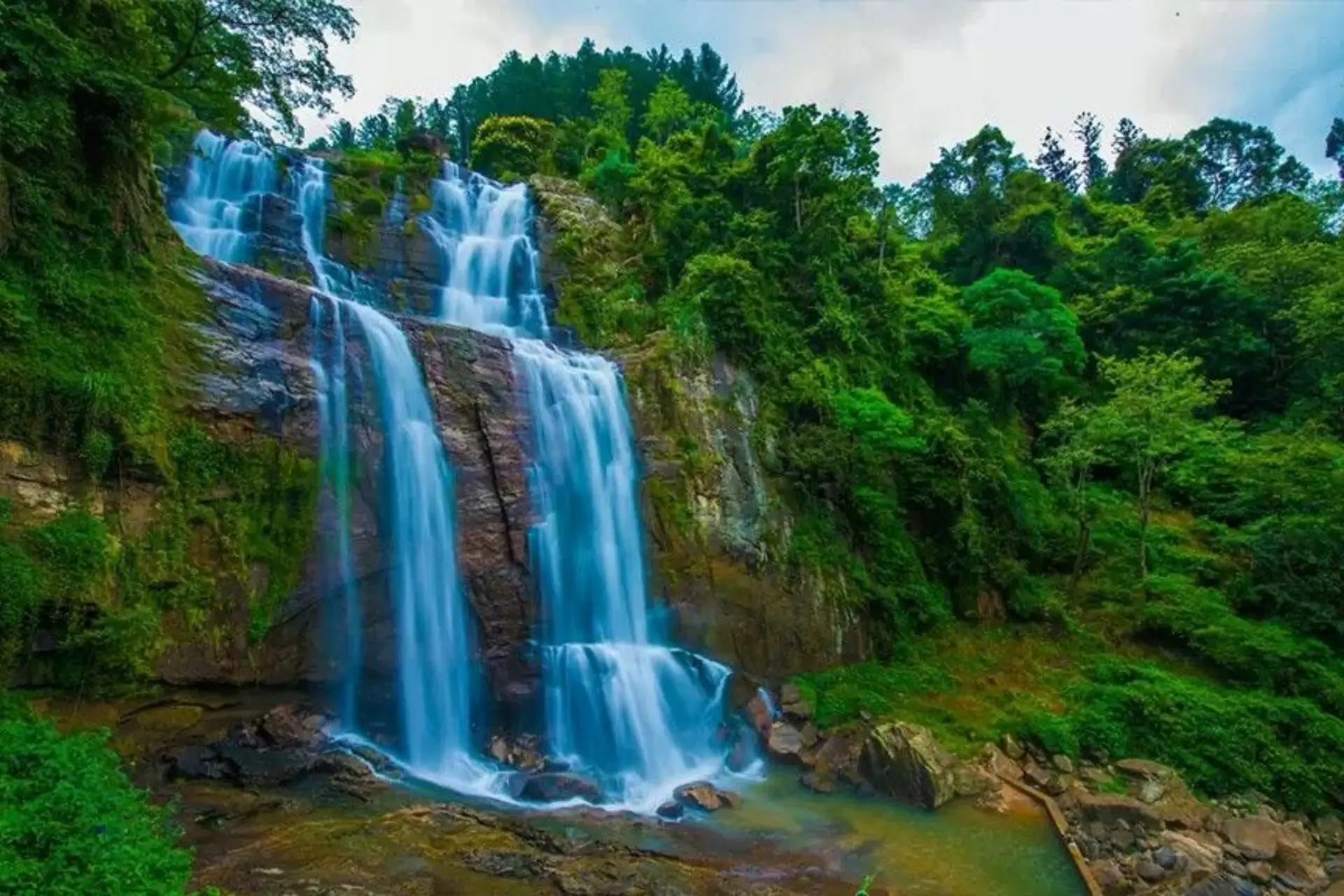 Ramboda Falls cascading down rocky cliff surrounded by green forest