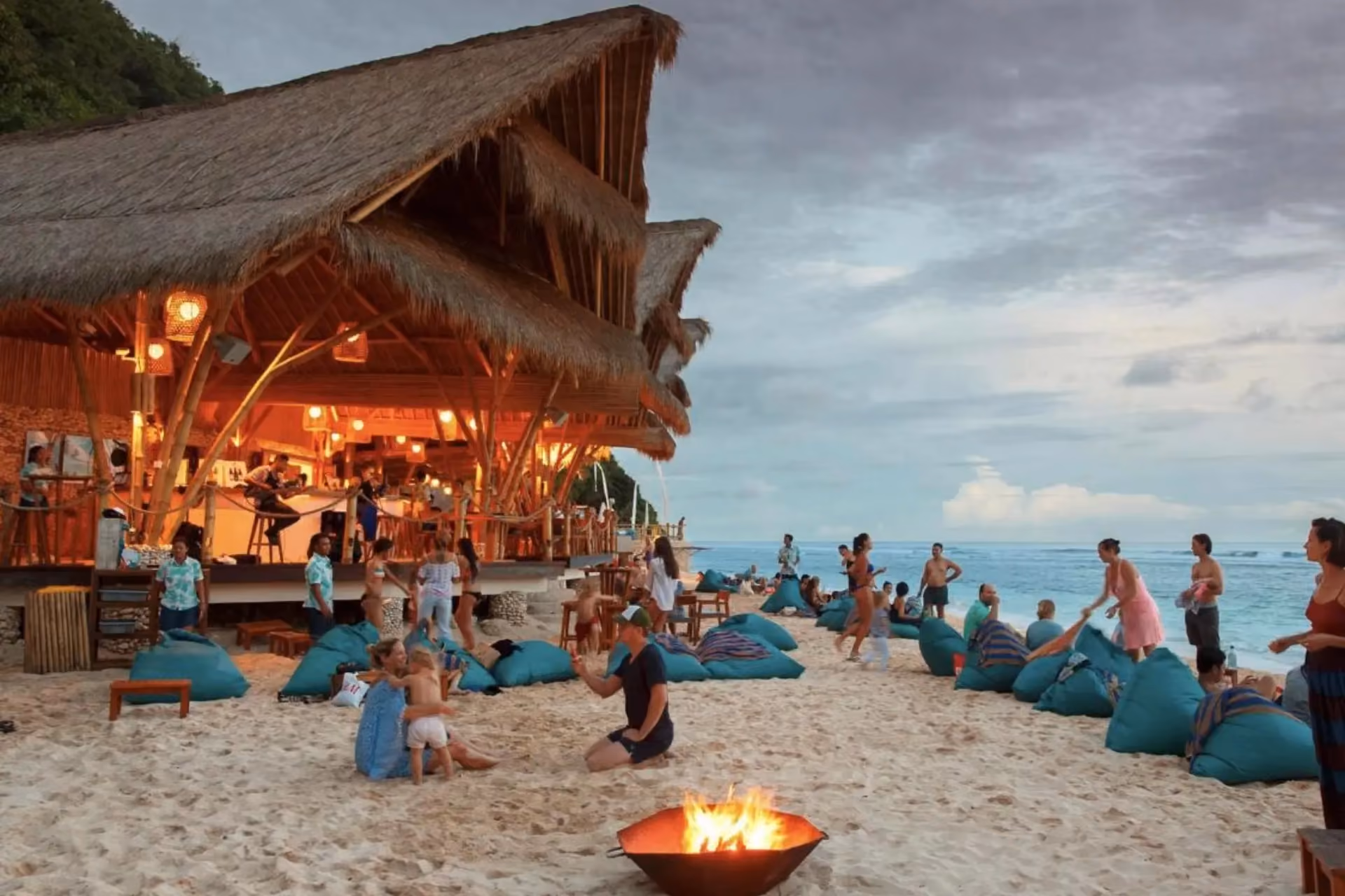 Beachfront party at Unawatanu Beach with fire pit and thatched roof shelter
