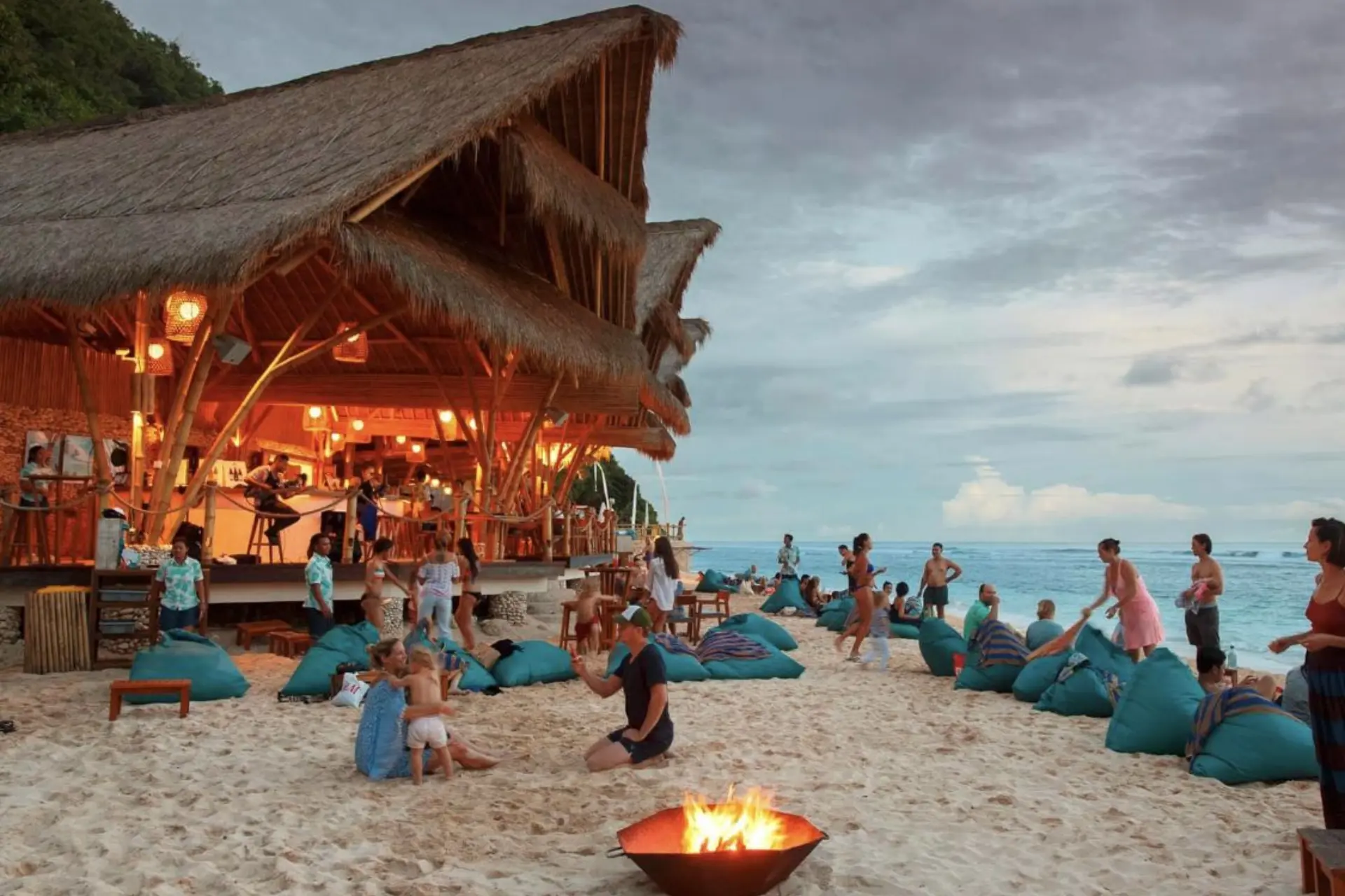 Beachfront party at Unawatanu Beach with fire pit and thatched roof shelter