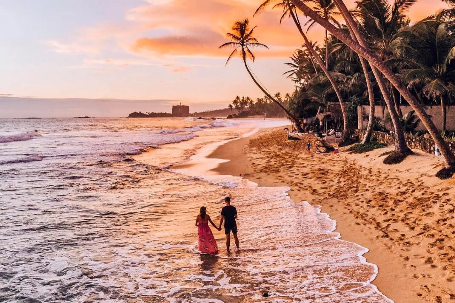 Couple wading in water at Unawatanu Beach at sunset