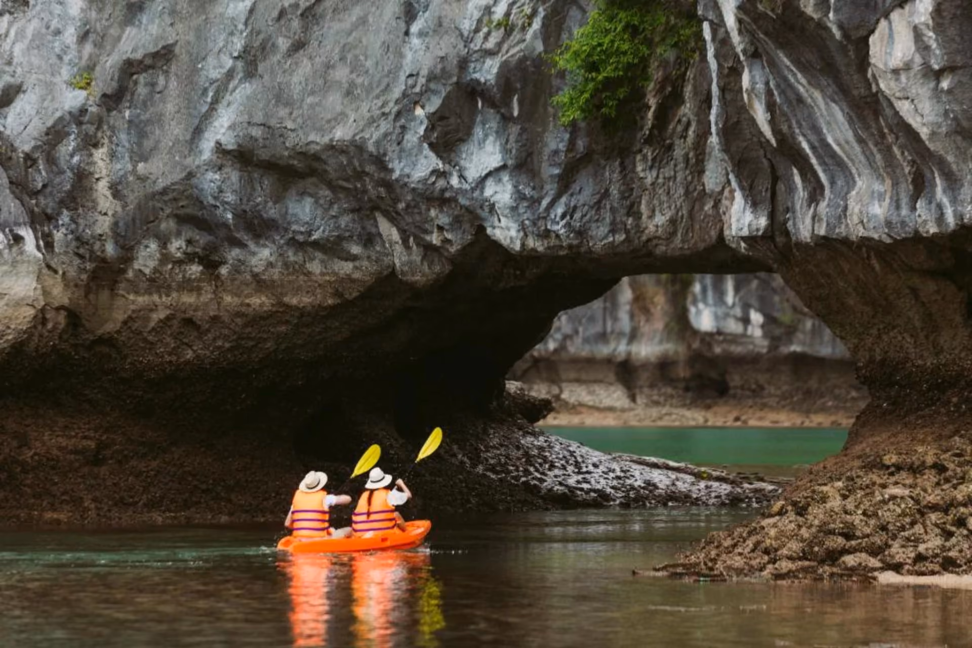 Two people kayaking under rock arch at La Regina