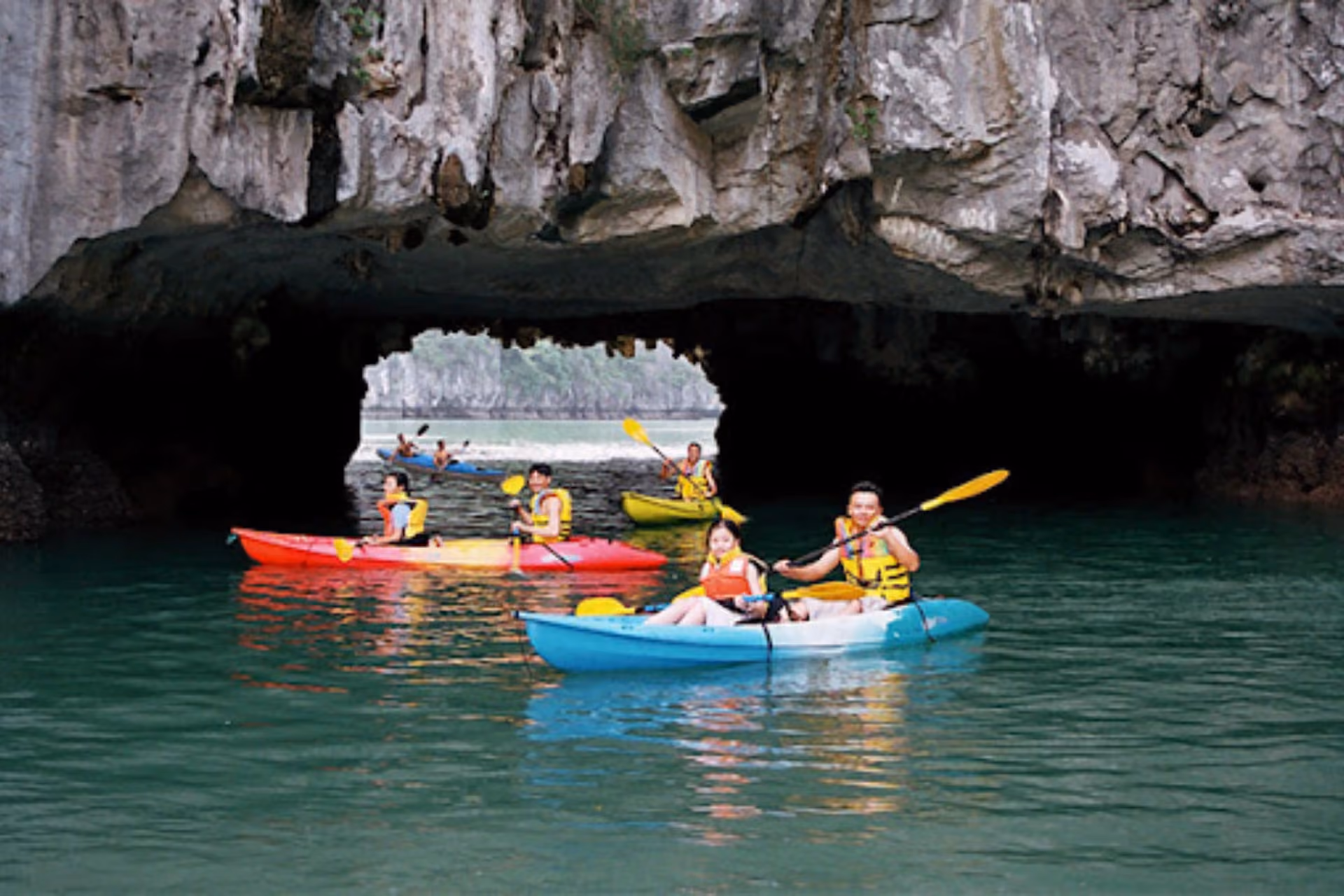 Kayakers paddling under limestone caves at Ha Long Bay