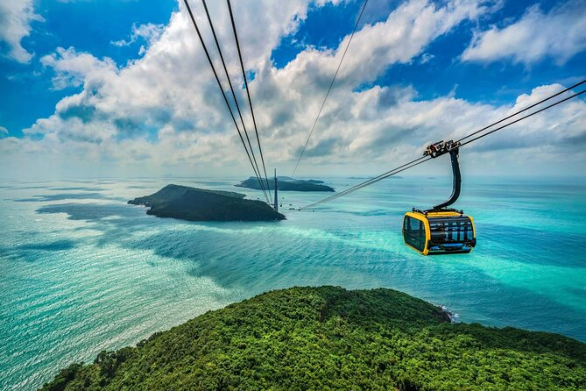 Yellow cable car over islands and blue water, Hon Thom