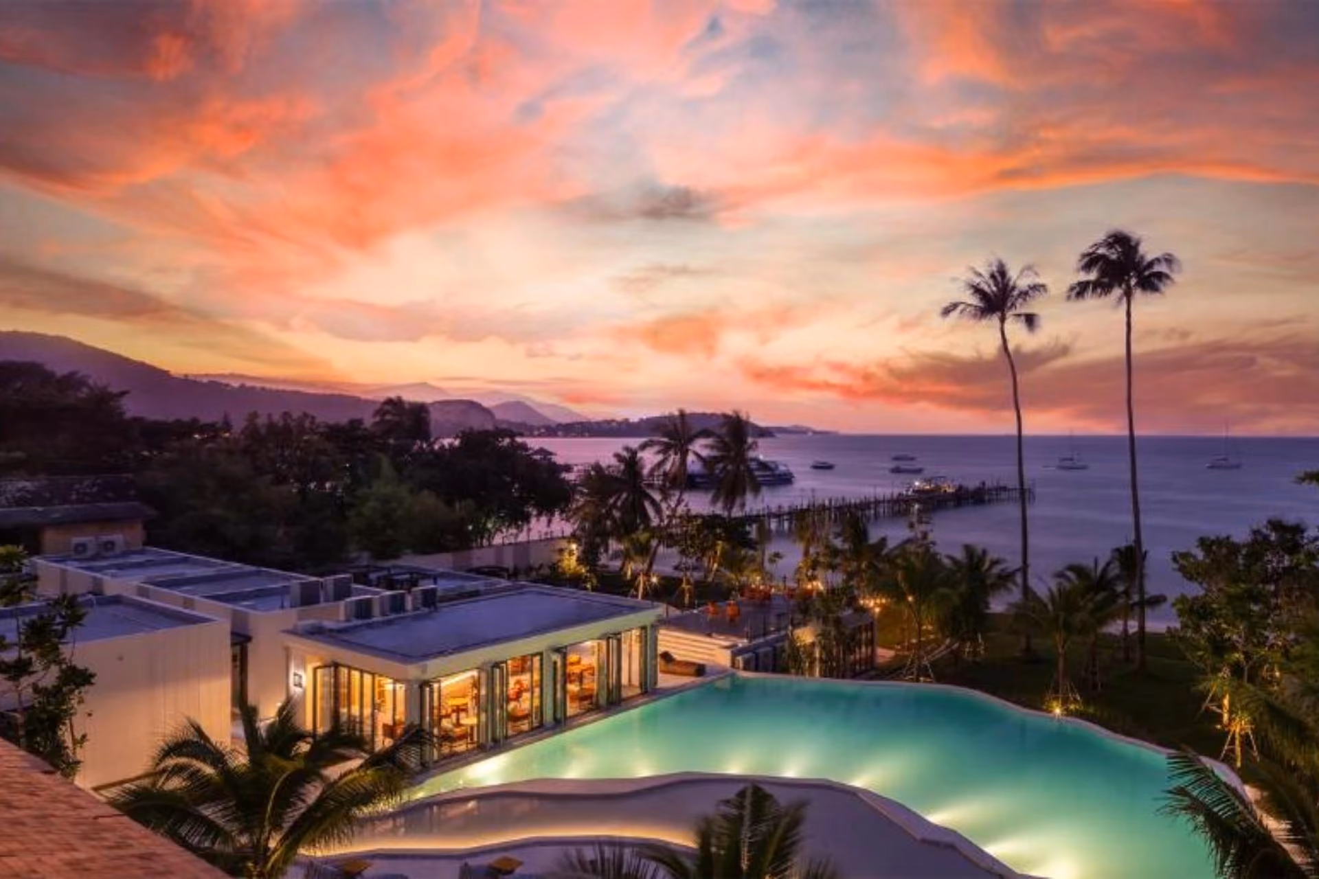 Luxury villa with glowing pool overlooking Samui bay at sunset