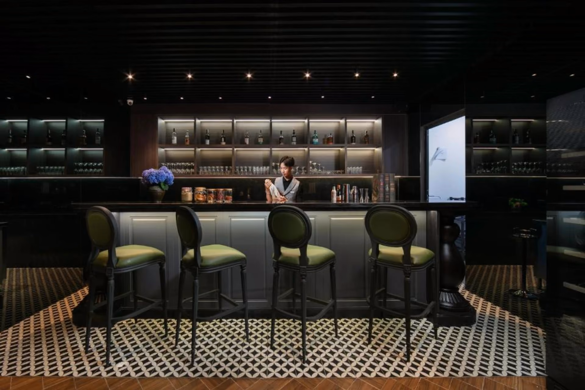 Modern bar at May De Ville Crown with green chairs and bottles