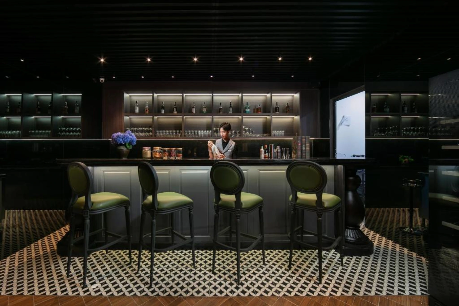 Modern bar at May De Ville Crown with green chairs and bottles