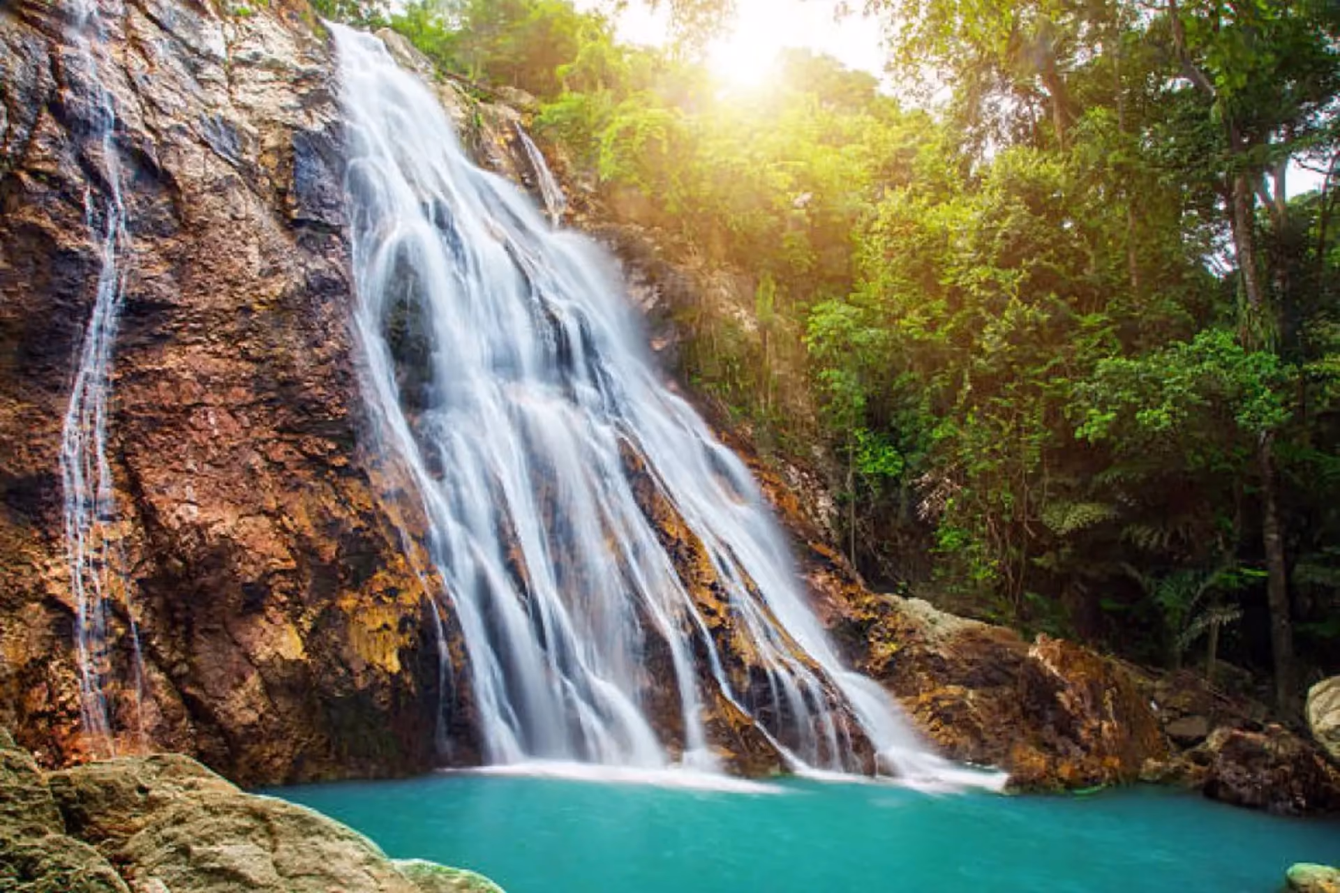Waterfall flowing into blue-green pool at Na Muang Koh Samui