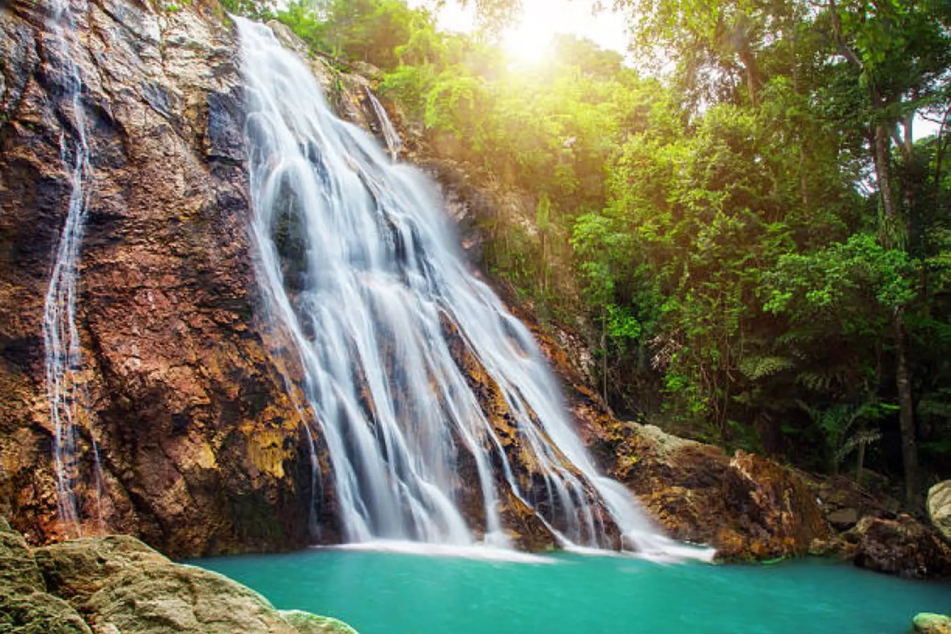 Waterfall flowing into blue-green pool at Na Muang Koh Samui