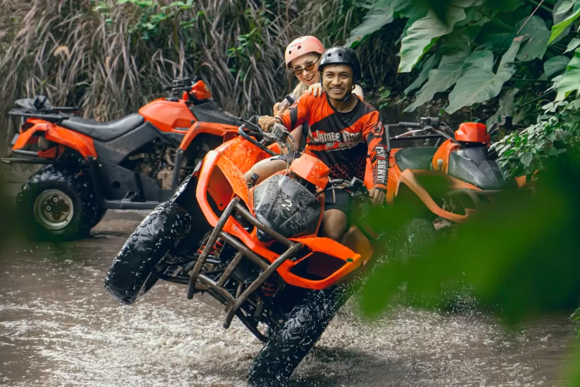 Two people on red ATV in Bali river water