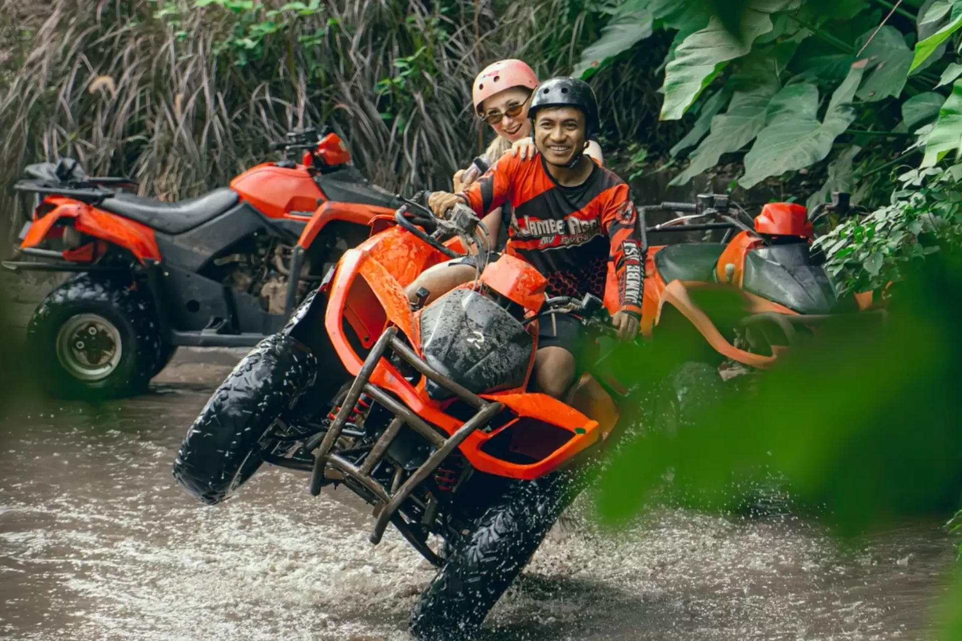 Two people on red ATV in Bali river water