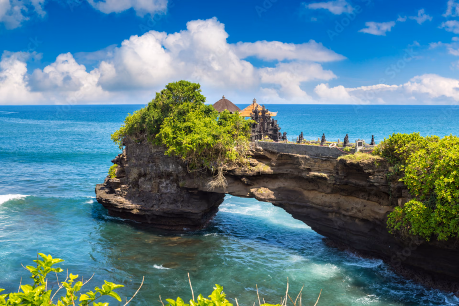 Batu Bolong Temple on rocky island in blue ocean