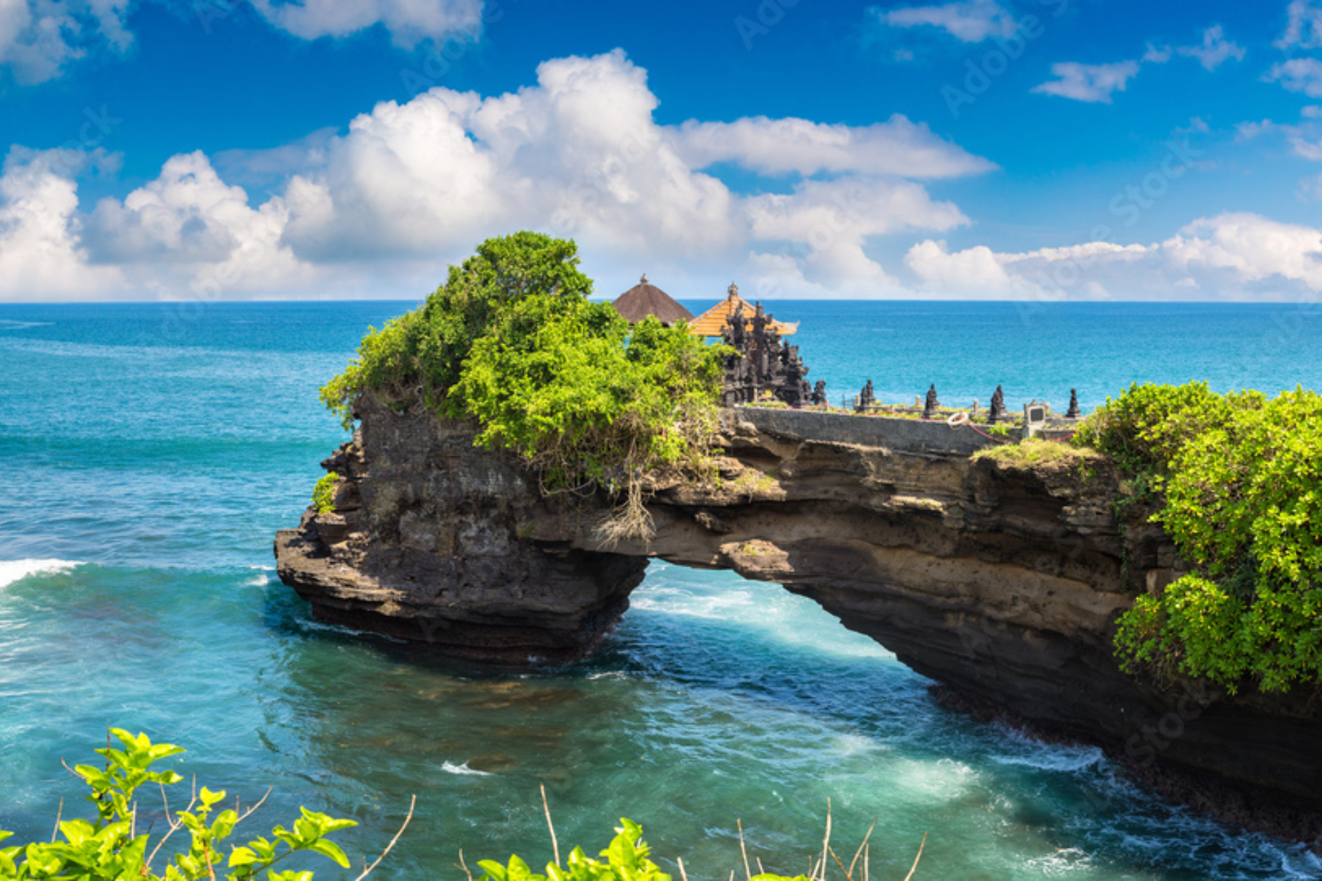 Batu Bolong Temple on rocky island in blue ocean