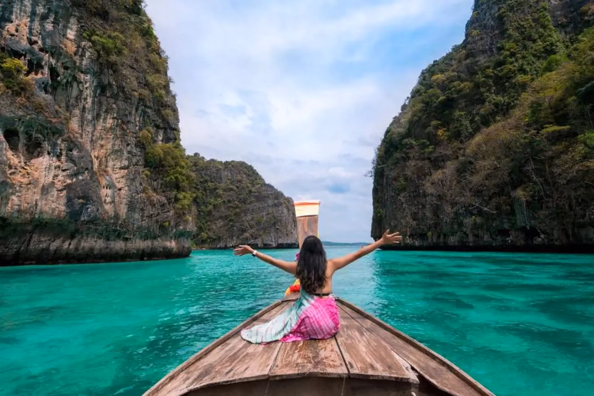 Woman on boat in Phuket with tall cliff walls