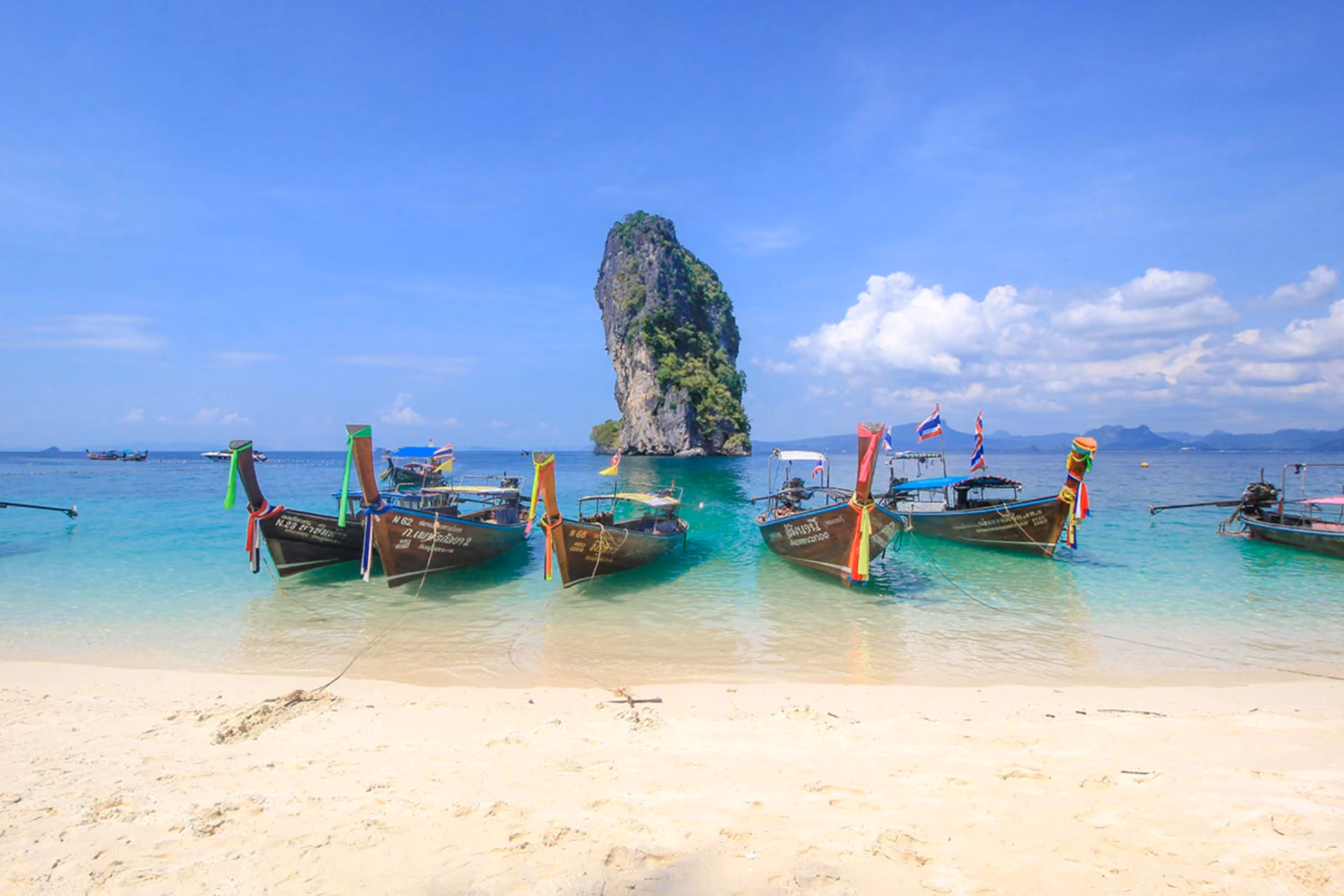 Traditional boats on beach in Krabi with rock island